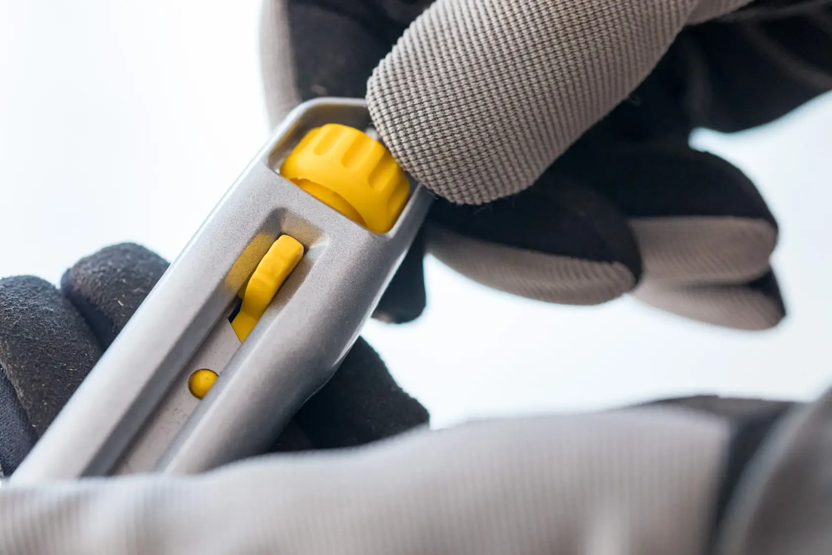 STANLEY 0-10-018 utility knife close-up, showing yellow adjustment wheel, held by gloved hand.
