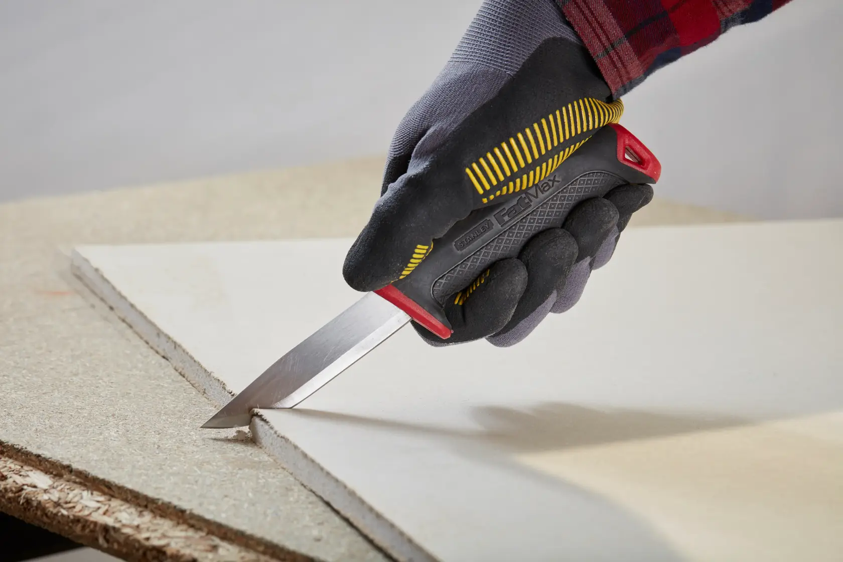 Photo of STANLEY 0-10-231 utility knife cutting drywall held by a gloved hand.