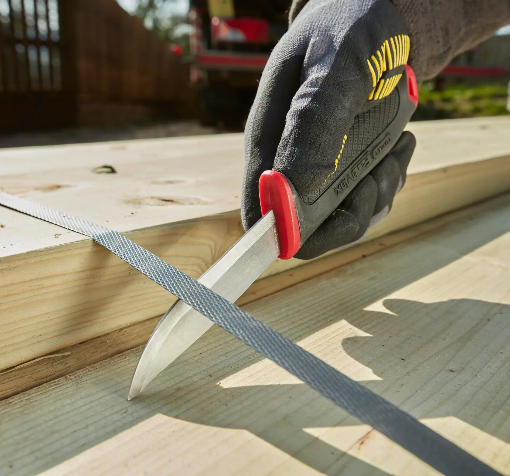 STANLEY 0-10-231 photography of utility knife with black and red handle held on wooden planks outdoors.