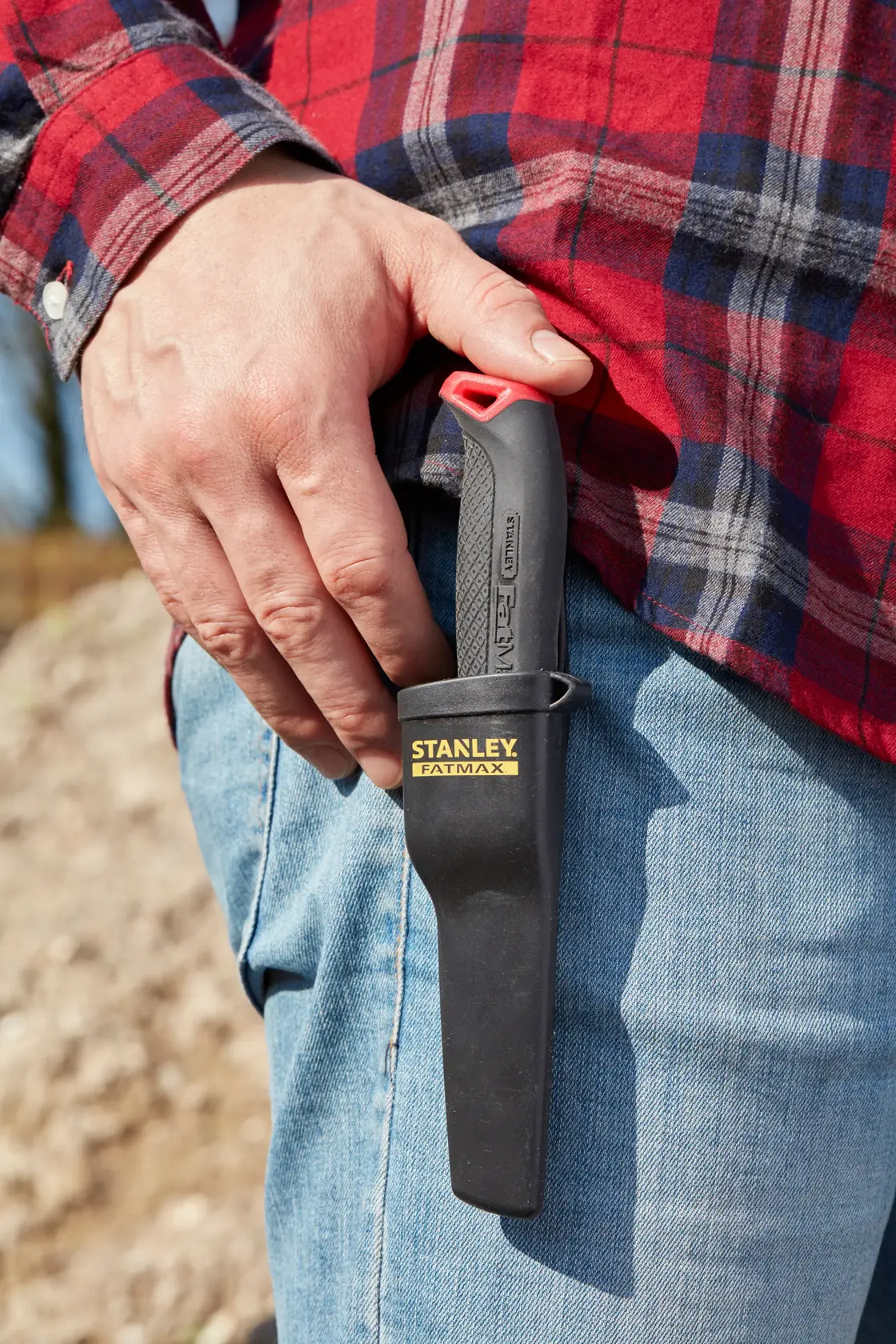 STANLEY 0-10-231 utility knife in black sheath clipped to jeans, person wearing red plaid shirt.