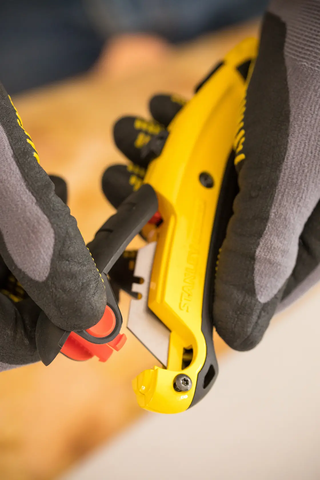 Photo of STANLEY 0-10-778 utility knife in yellow and black being used with gloved hands.