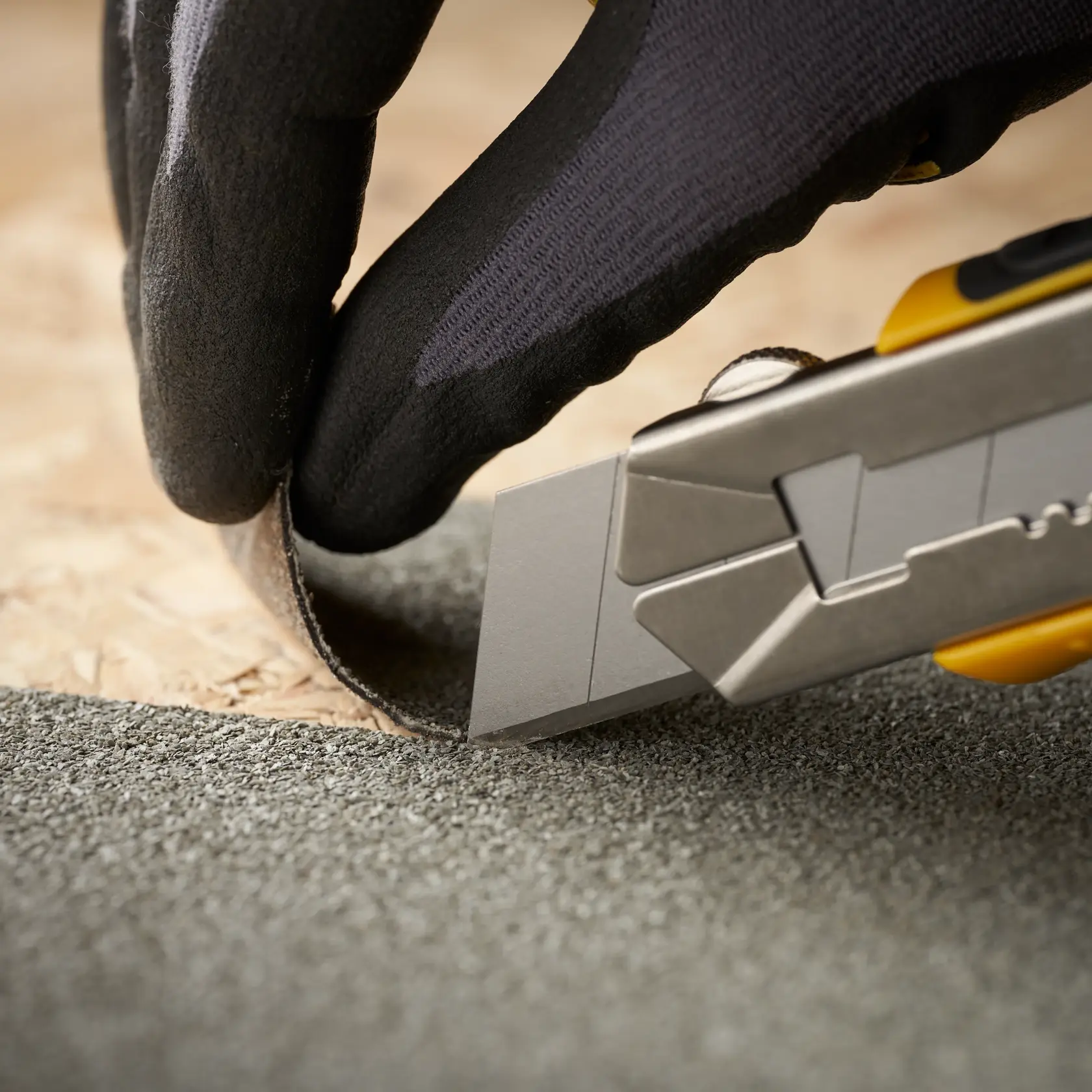 STANLEY 0-11-325 utility knife cutting roofing material, close-up photo shows blade edge and gloved hand.