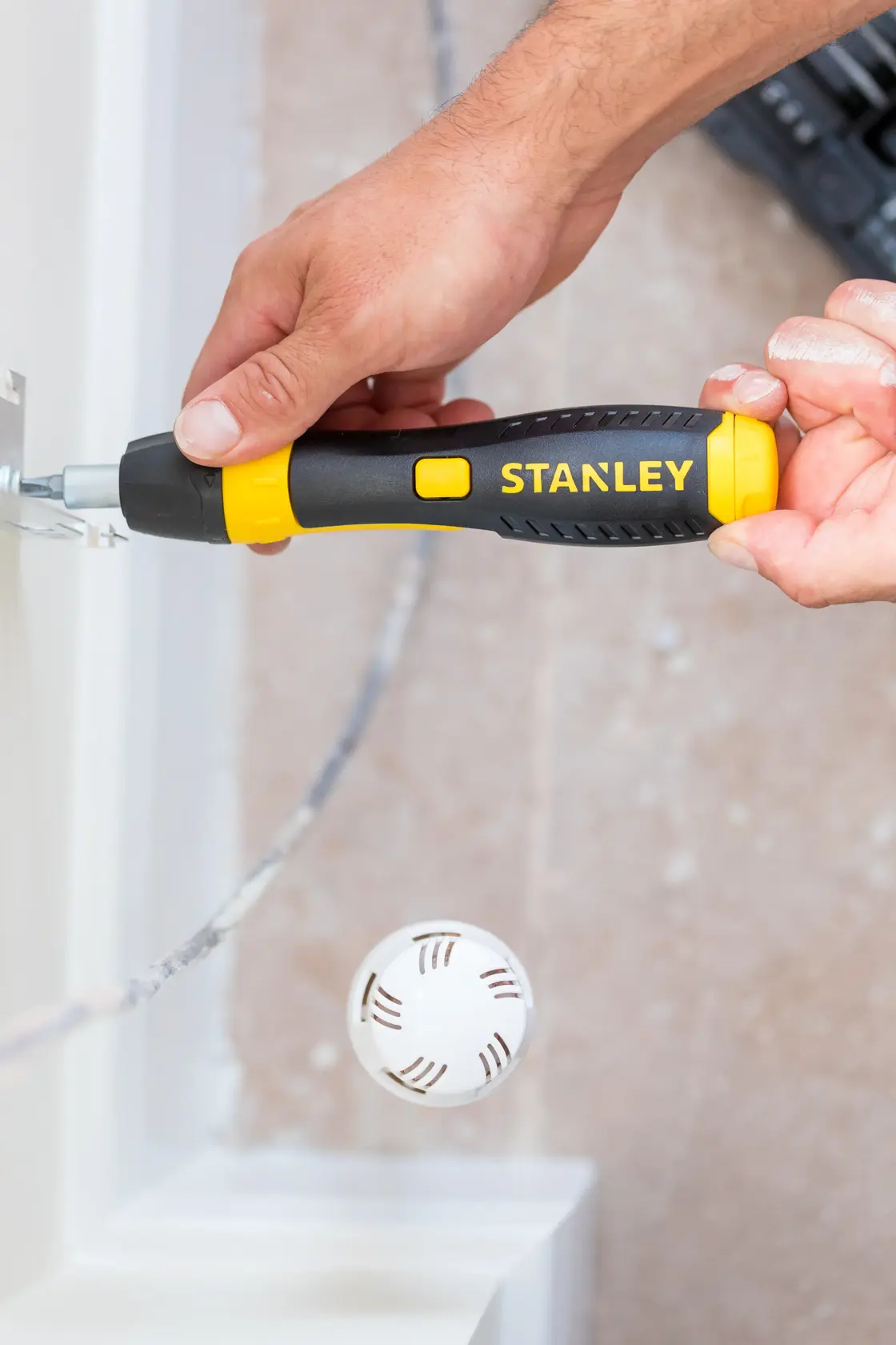 Photography of STANLEY 0-63-038 screwdriver with yellow and black handle in use near a wall.