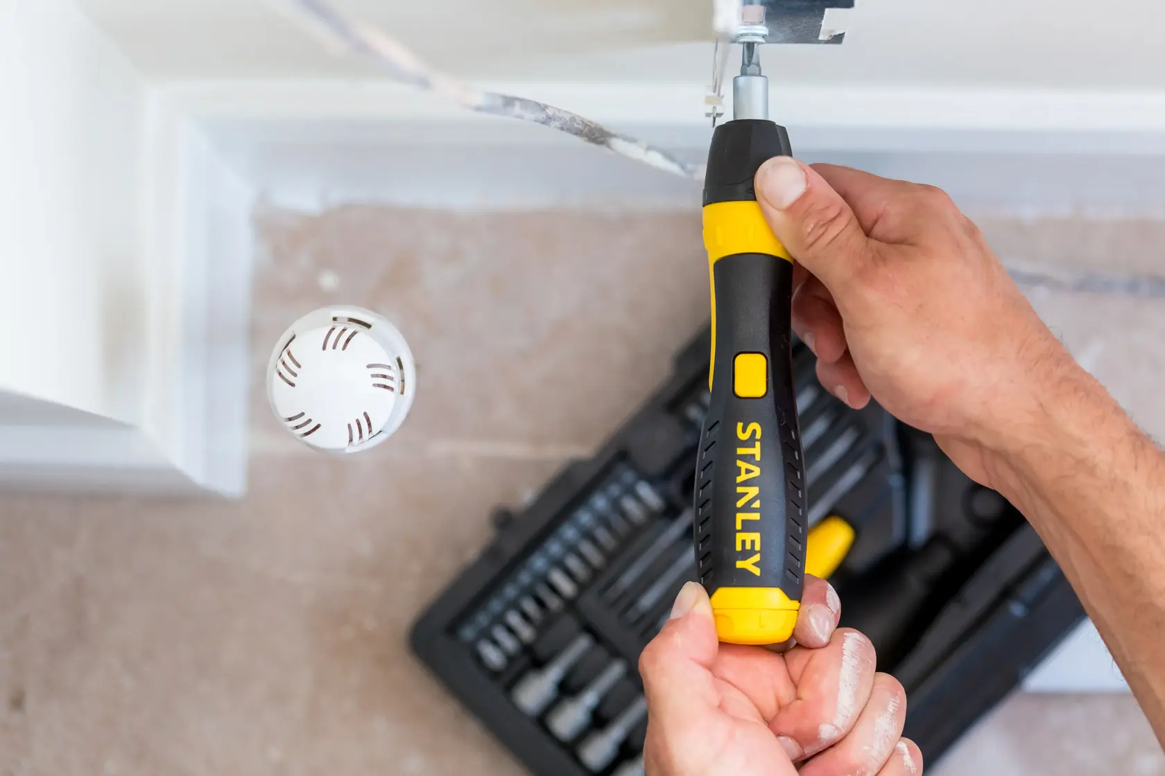 STANLEY 0-63-038 ratcheting screwdriver set in use, black and yellow handle, top view, toolkit in background.