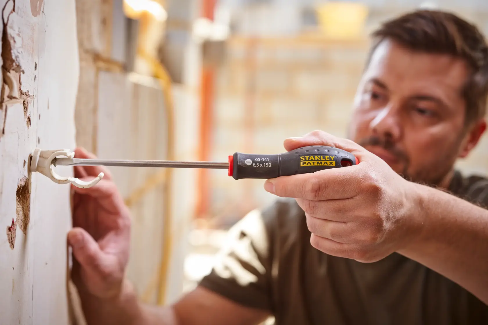 STANLEY 0-65-141 screwdriver with black and yellow handle used to install wall bracket, photo shows tool in use.