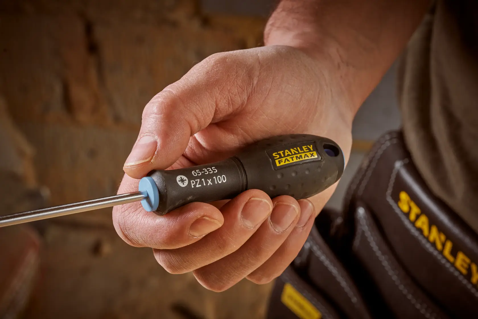 Photo of STANLEY 0-65-335 screwdriver with black ergonomic handle and yellow branding held in hand.