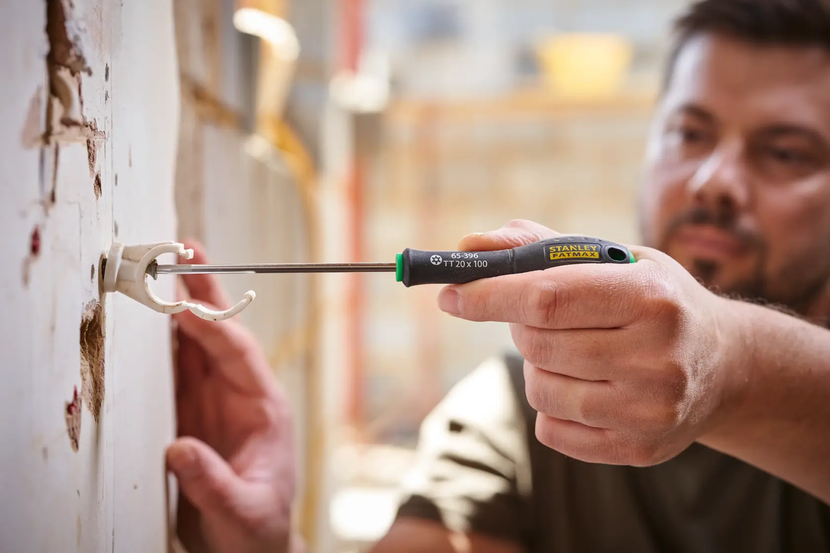 Photo of STANLEY 0-65-396 screwdriver being used to secure a wall bracket, close-up of hand and tool in action.