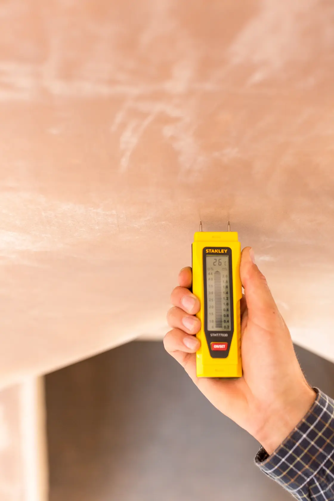 Photo of STANLEY 0-77-030 moisture meter used on plaster wall, held in hand.