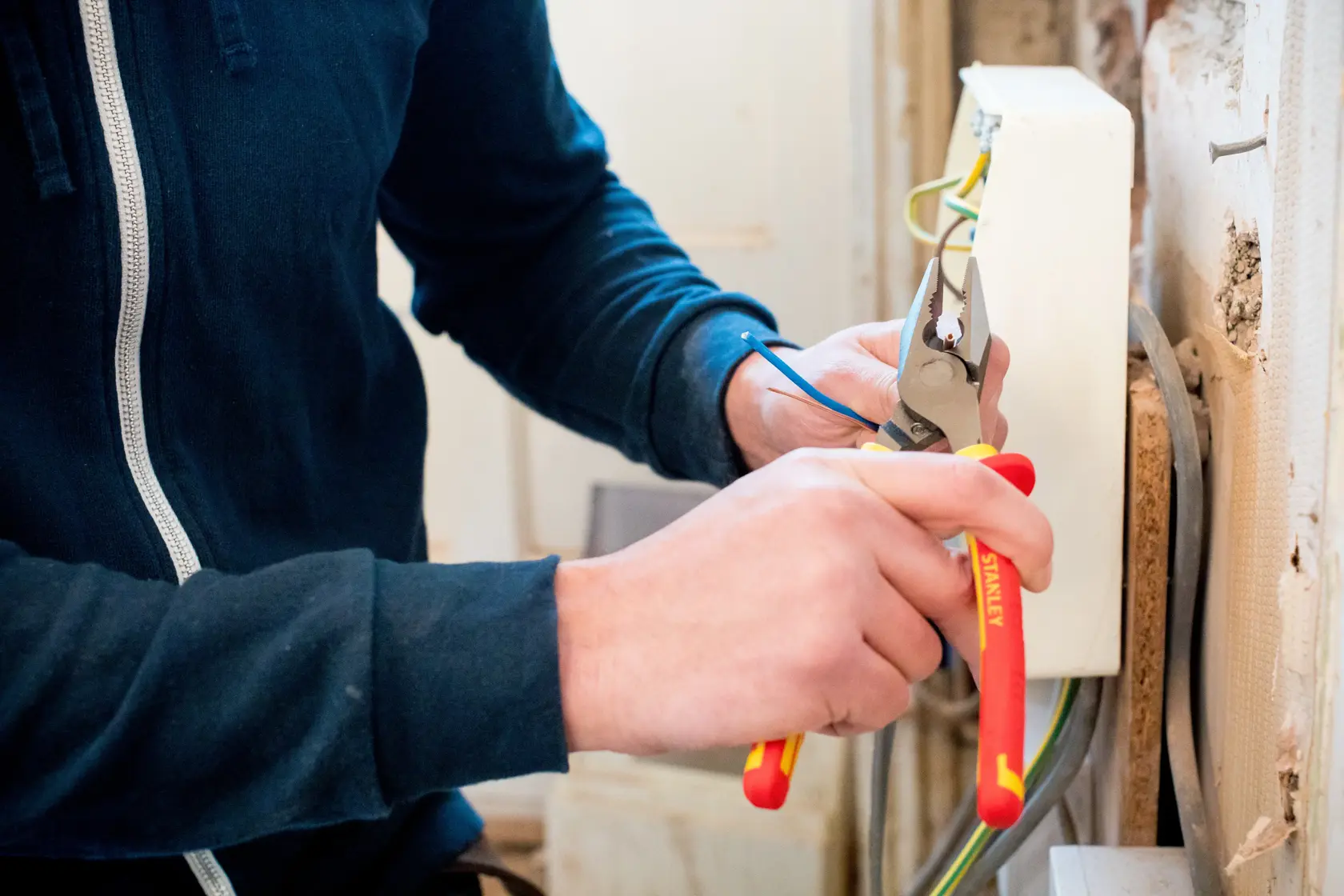 Photo of STANLEY 0-84-001 insulated pliers cutting electrical wire during installation.