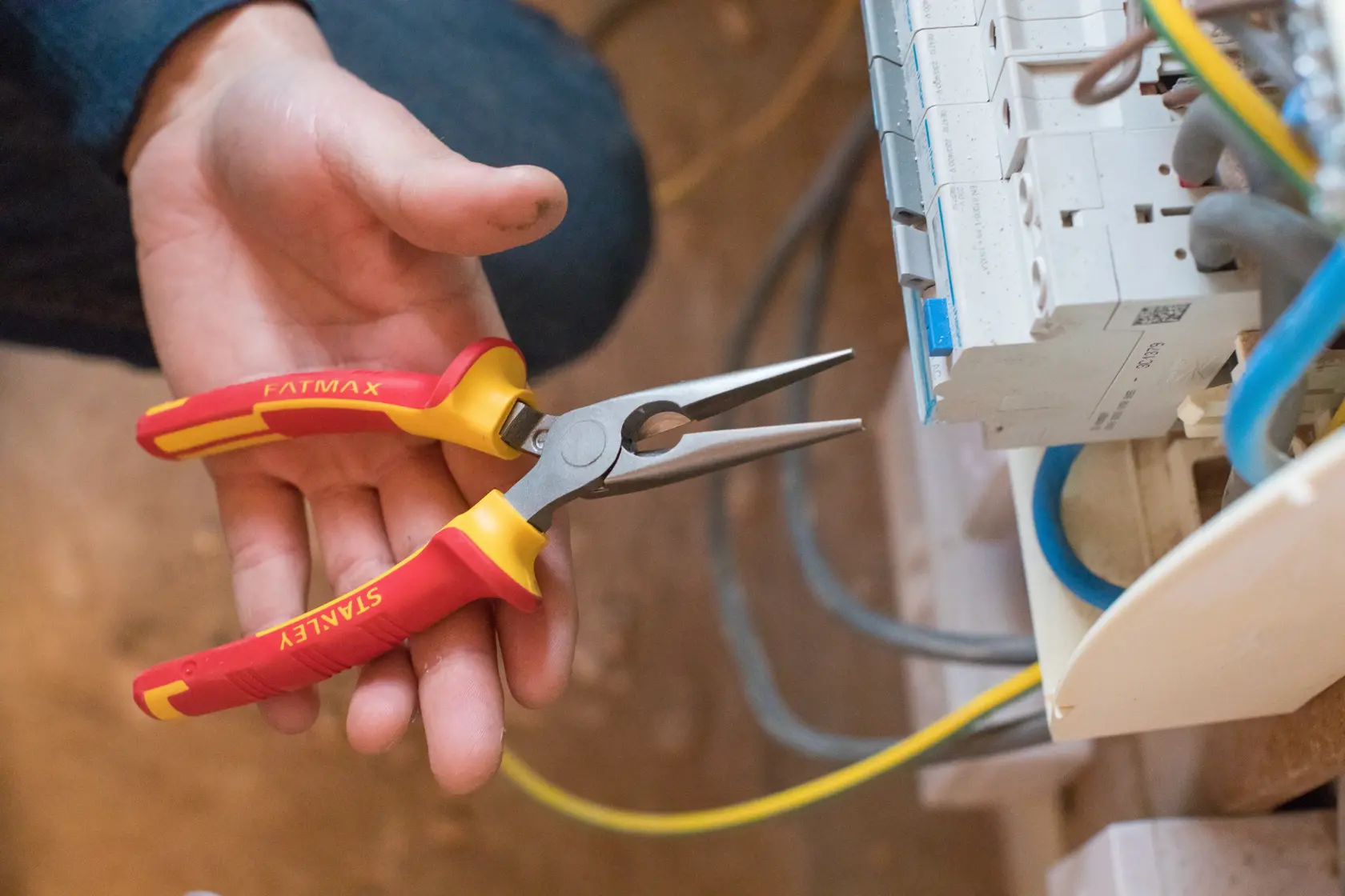 STANLEY 0-84-006 long nose pliers with red and yellow handle held near electrical panel.