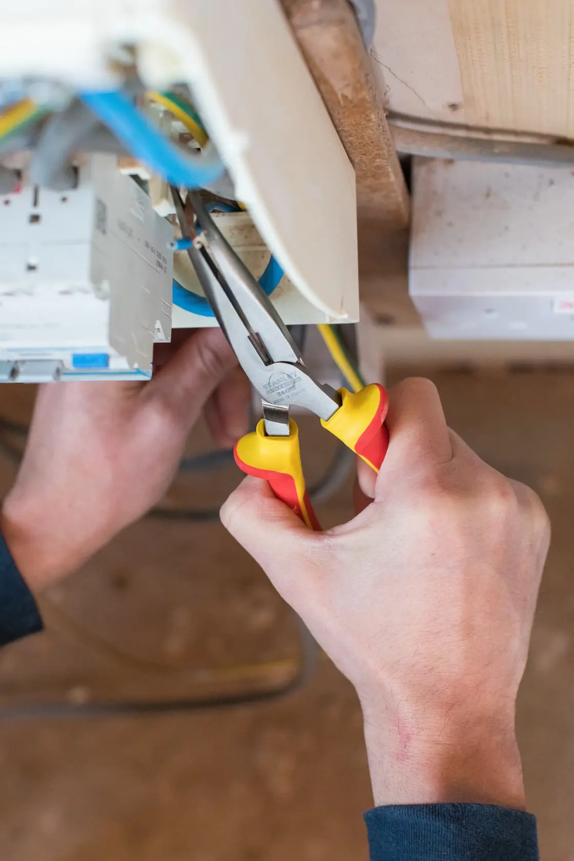 STANLEY 0-84-008 insulated long nose pliers in use, red and yellow handles, electrical wiring application.