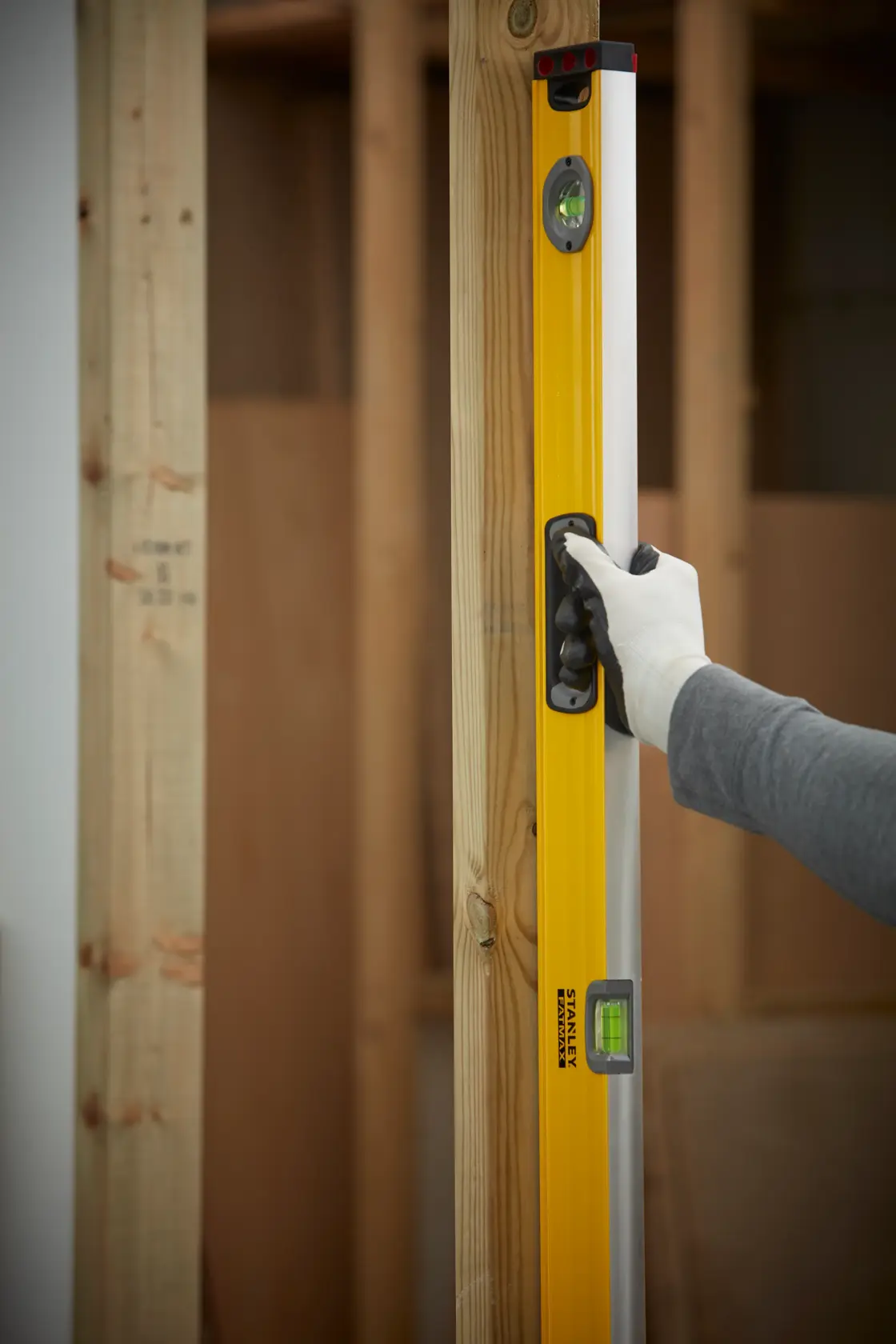 STANLEY 1-43-548 level tool held vertically against wooden frame, user wearing glove.