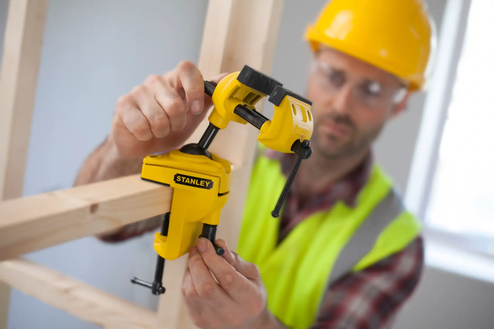 STANLEY 1-83-069 yellow clamp being used to secure wooden beams, close-up photography.