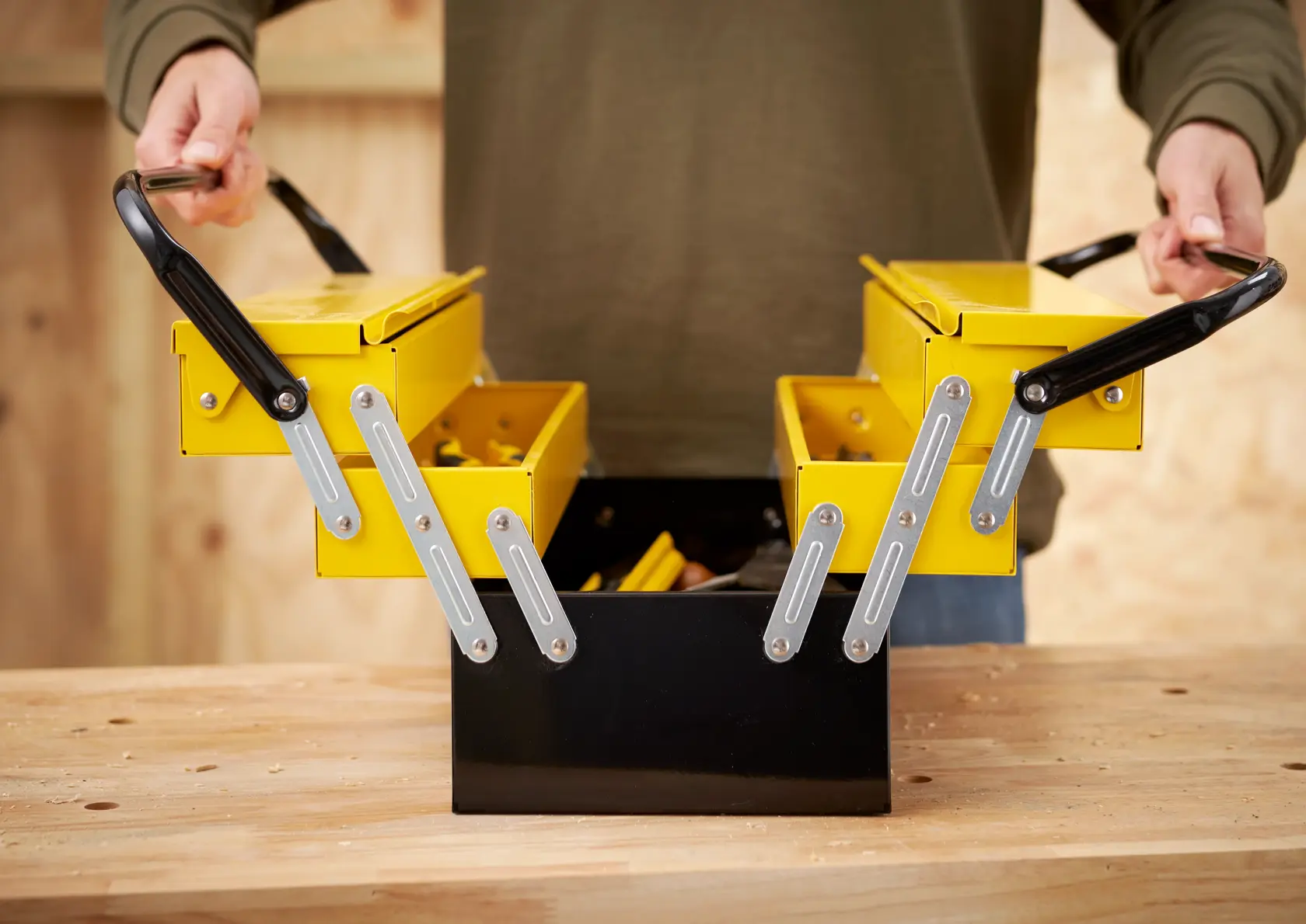 STANLEY 1-94-738 metal cantilever toolbox open on a workbench, showing yellow compartments and black handles.
