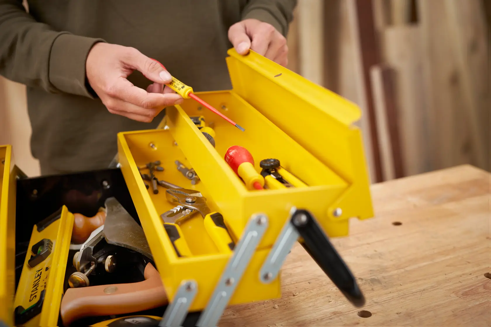 STANLEY 1-94-738 yellow metal toolbox with assorted hand tools, photo from above on a workbench.