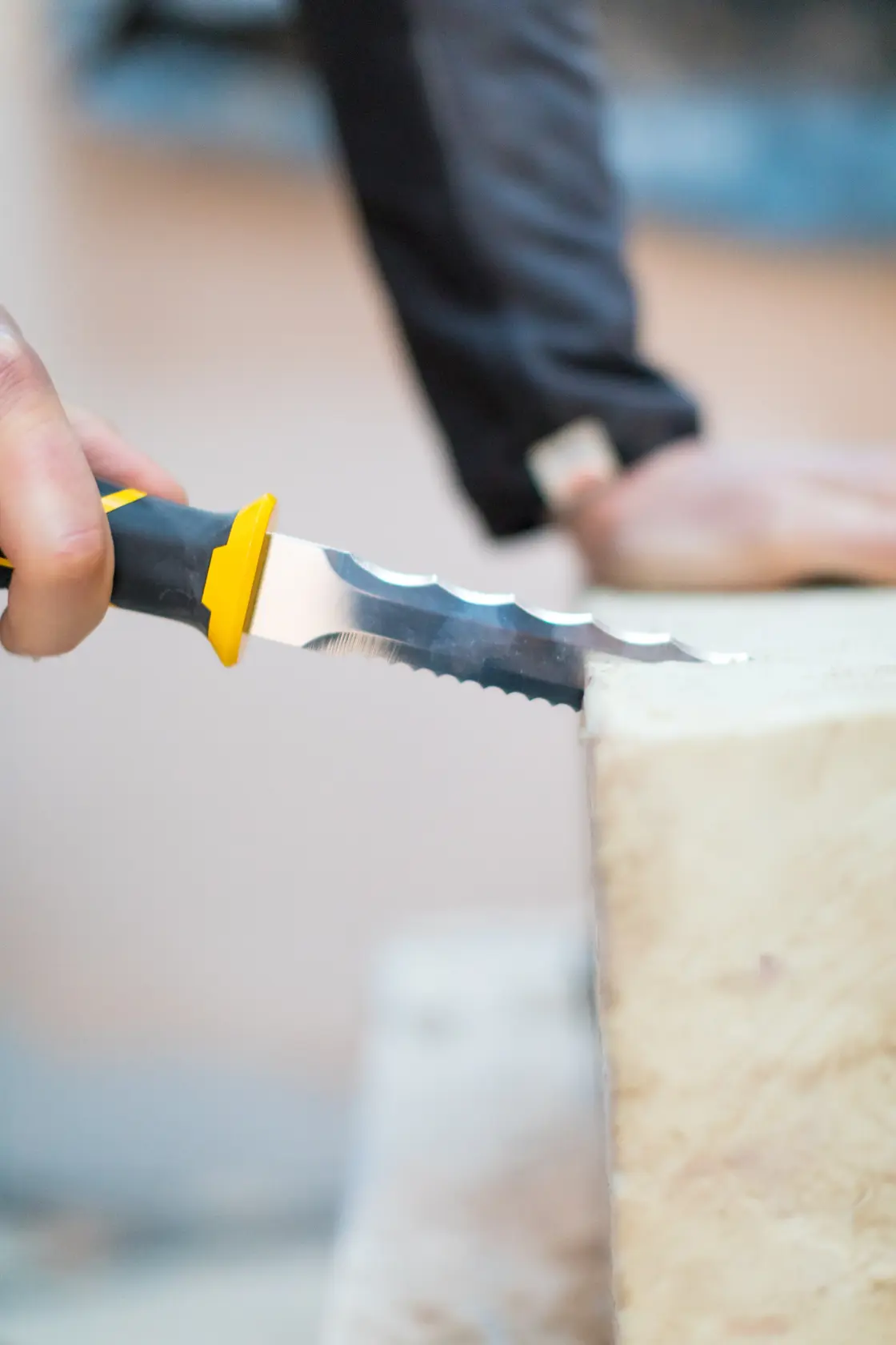 Photo of STANLEY FMHT0-10327 insulation knife with serrated blade cutting yellow insulation material.