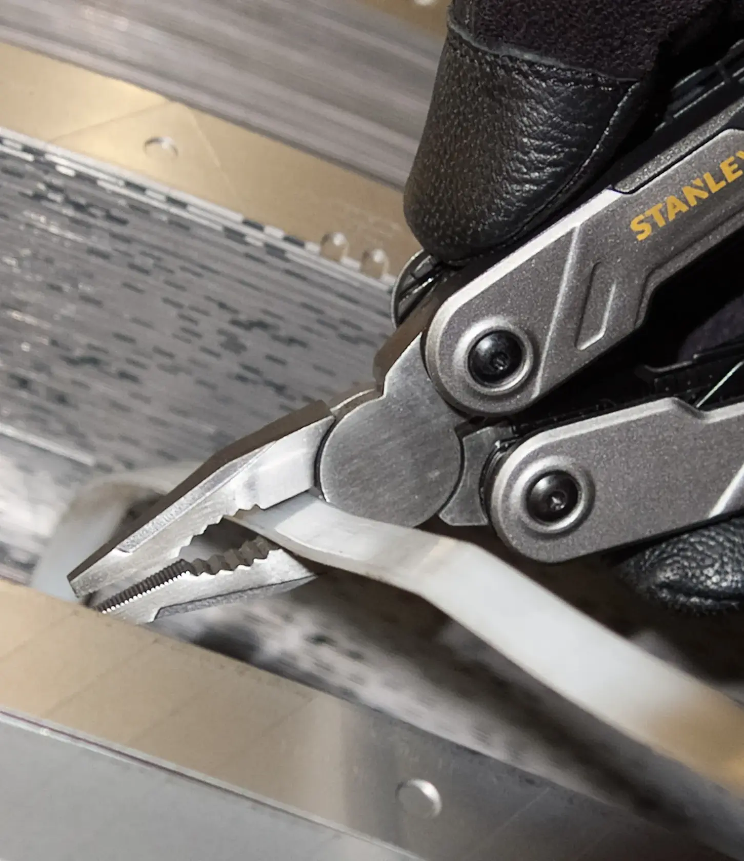 STANLEY FMHT0-72414 multitool pliers gripping a white cable, close-up photo.