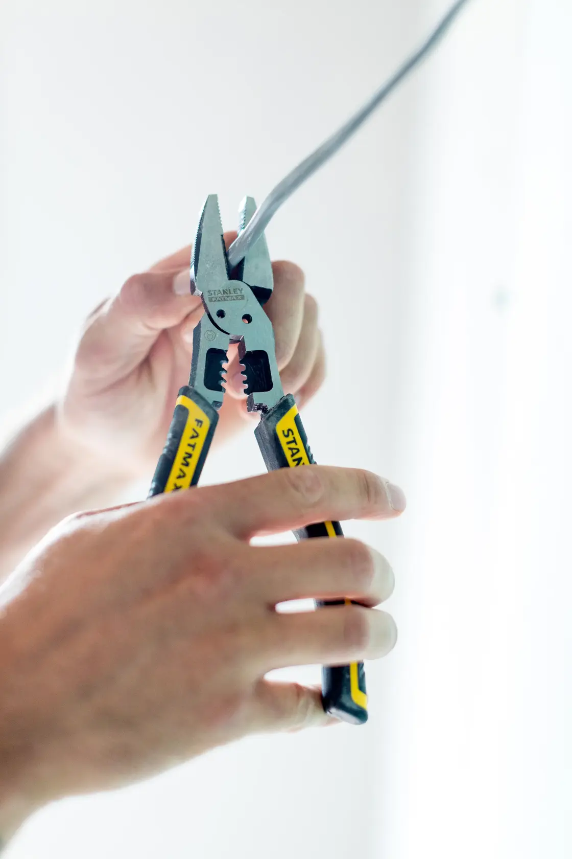 STANLEY FMHT0-75469 FATMAX pliers with yellow and black handles strip electrical wire in hand.