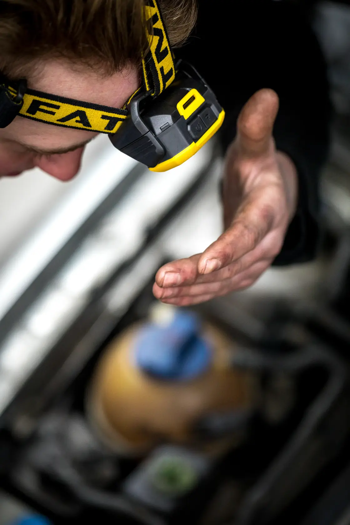STANLEY FMHT81509-0 headlamp on person working with dirty hand near machinery, close-up photography.