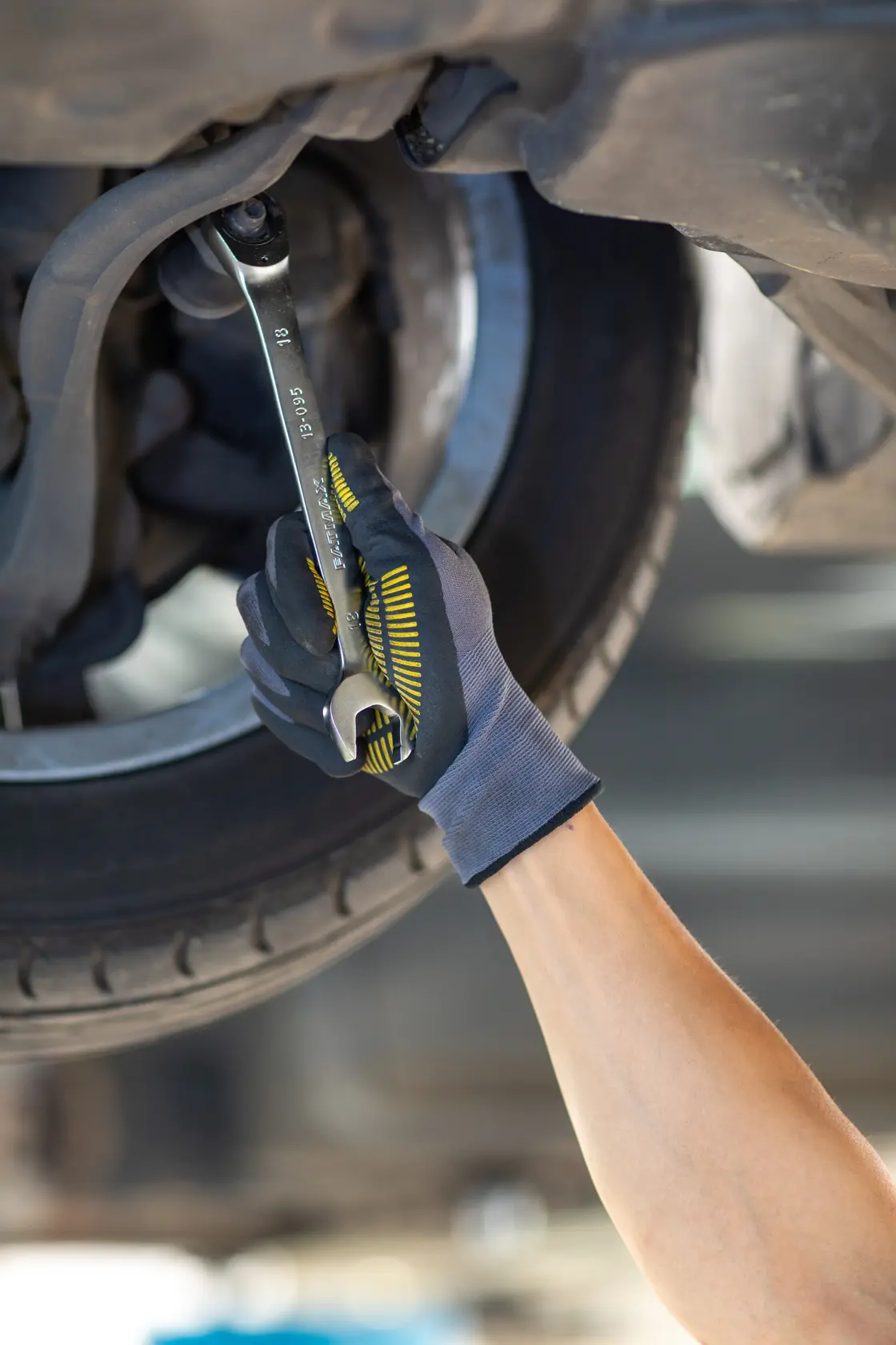 STANLEY FMMT13085-0 wrench used by gloved hand on car part, close-up photography.
