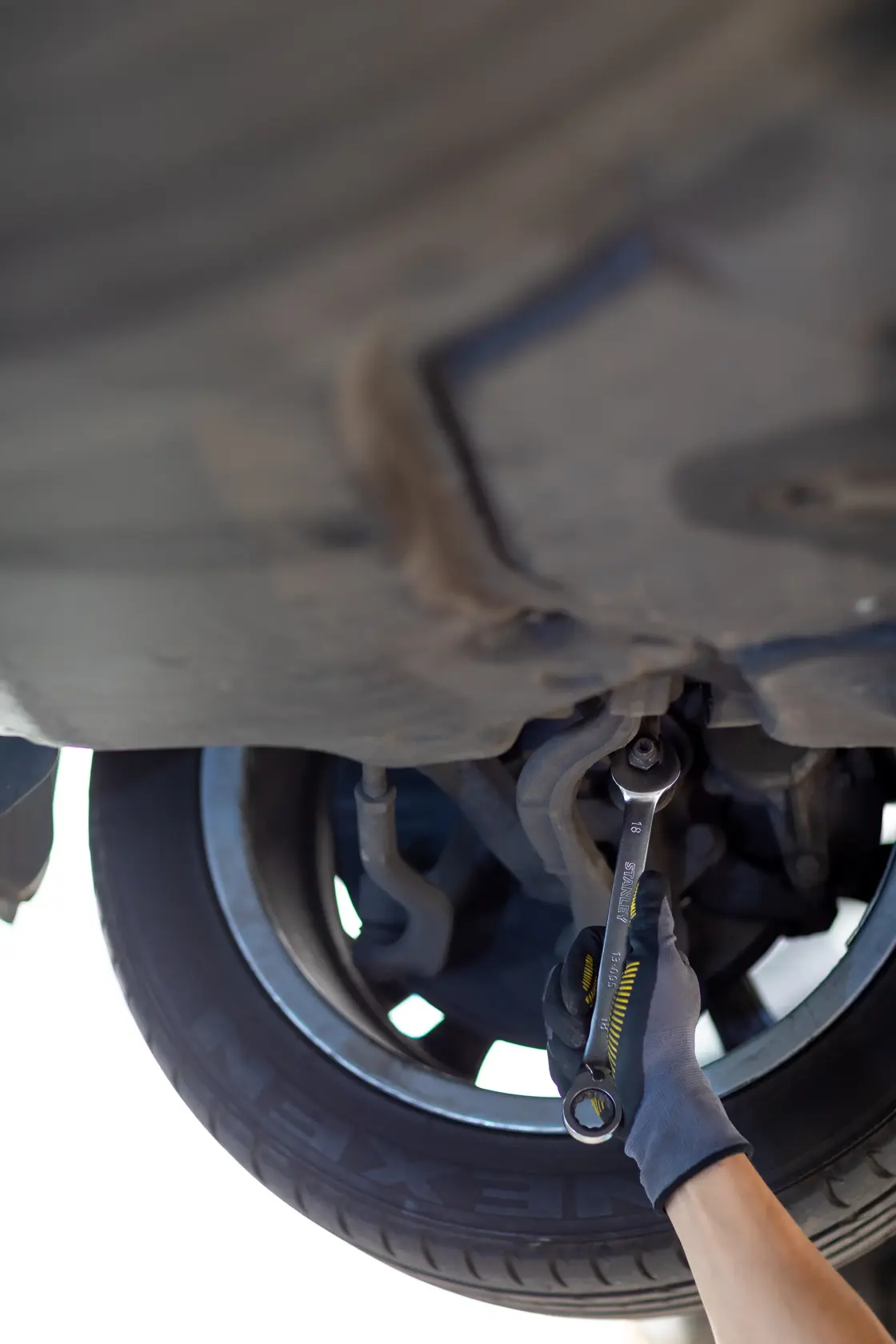 STANLEY FMMT13089-0 wrench used under car near wheel, photography of tool in automotive repair context.