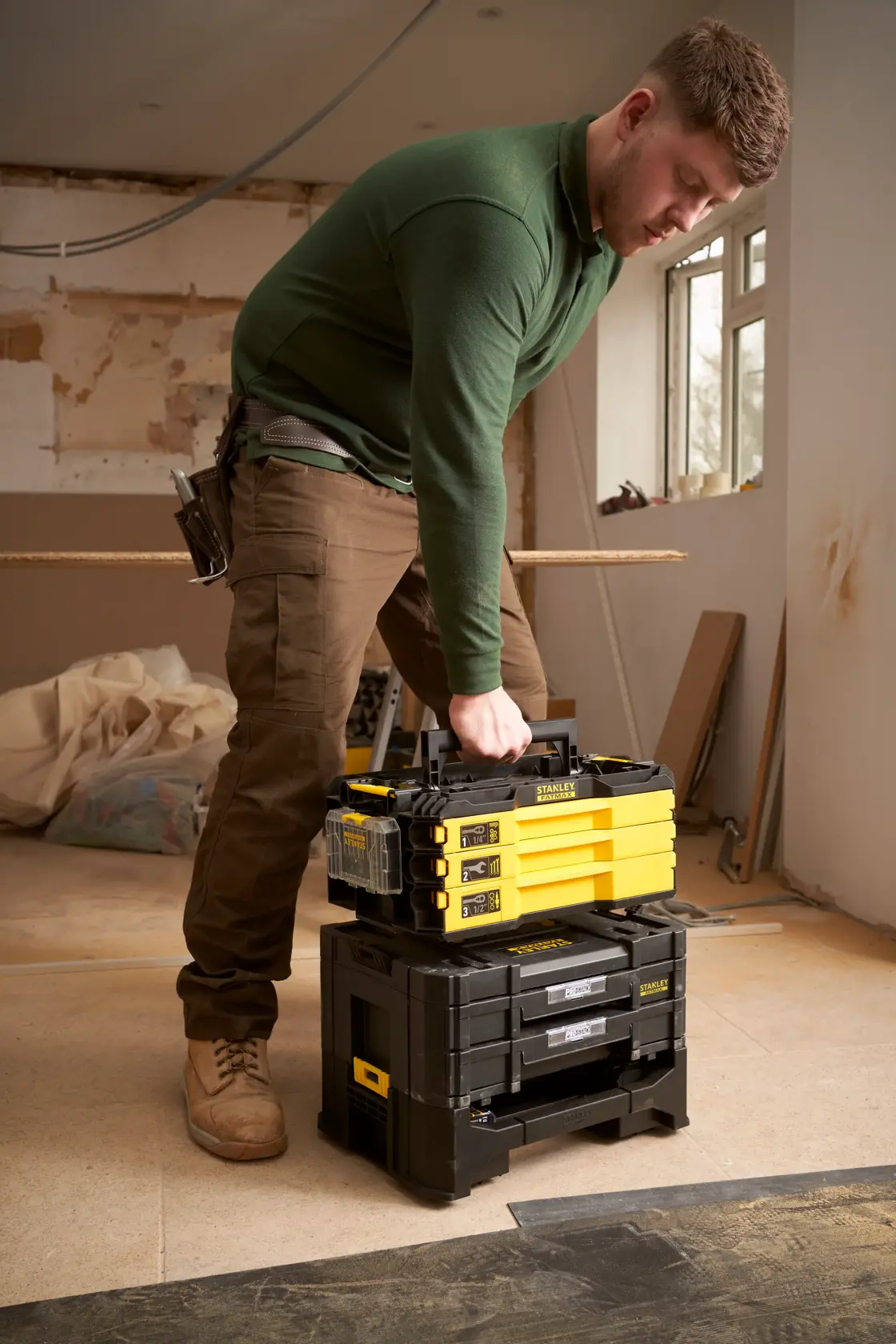 STANLEY FMMT98107-1 tool storage stack, yellow and black, carried by person in workshop setting.