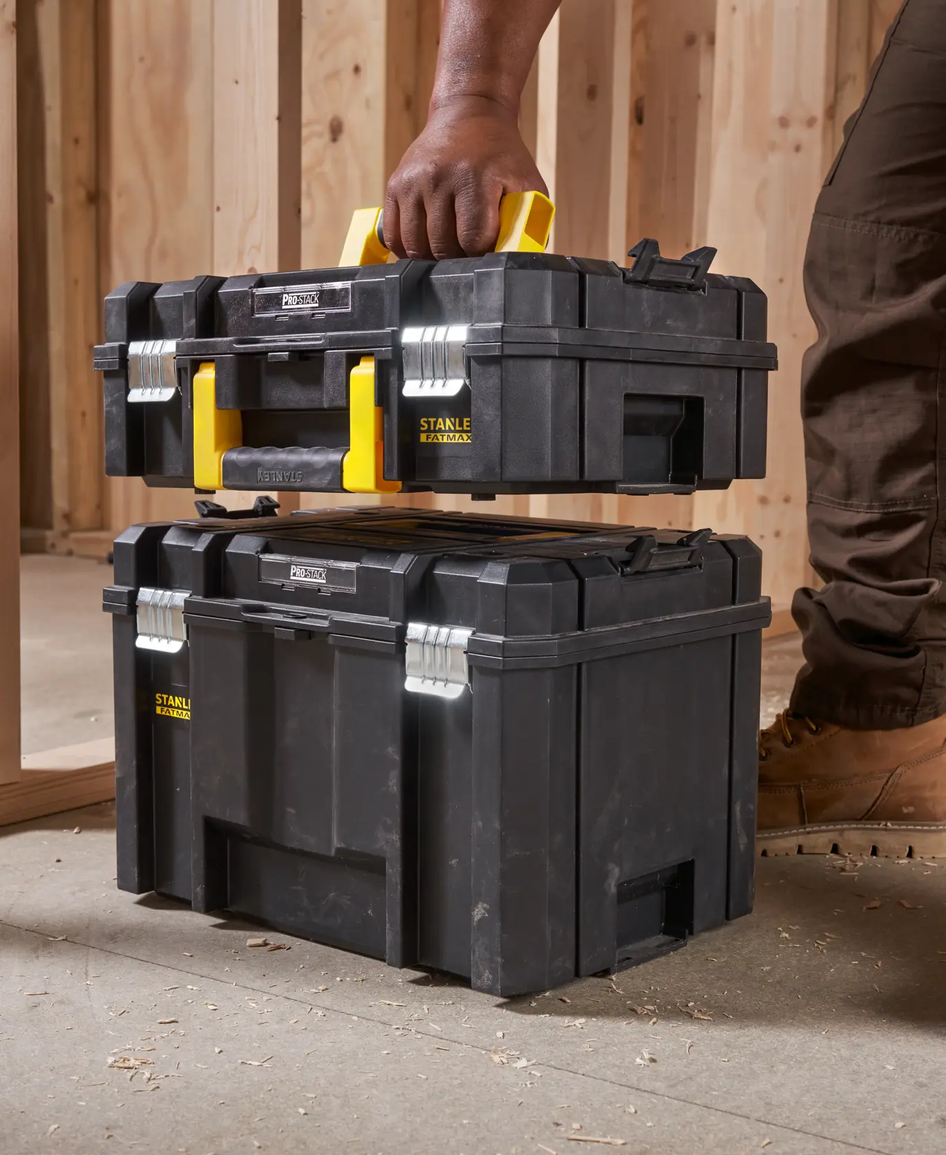 STANLEY FMST1-71966 black toolbox with yellow handle, side angle, stacked in construction site.