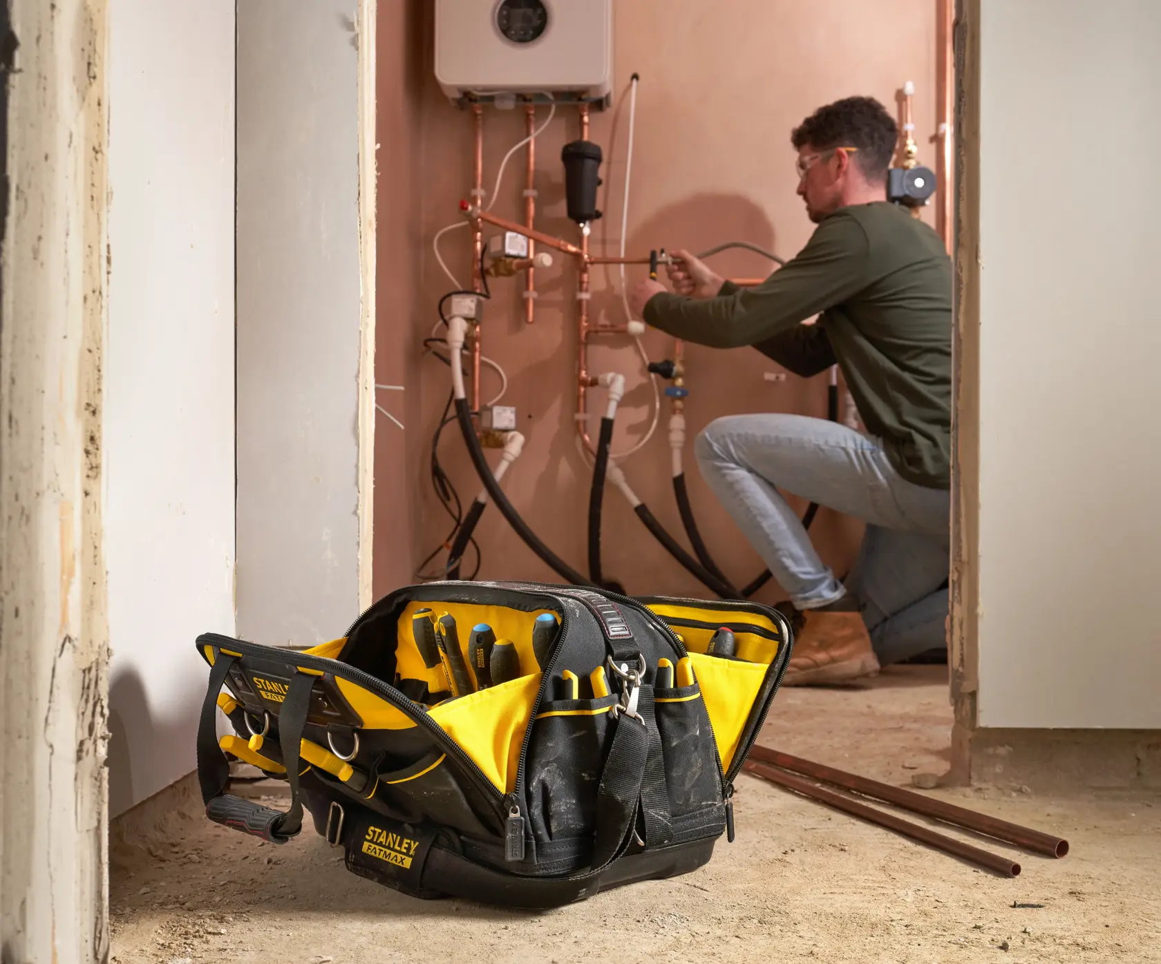 Photo of STANLEY FMST1-73607 tool bag with yellow and black compartments, filled with tools, in a worksite room.