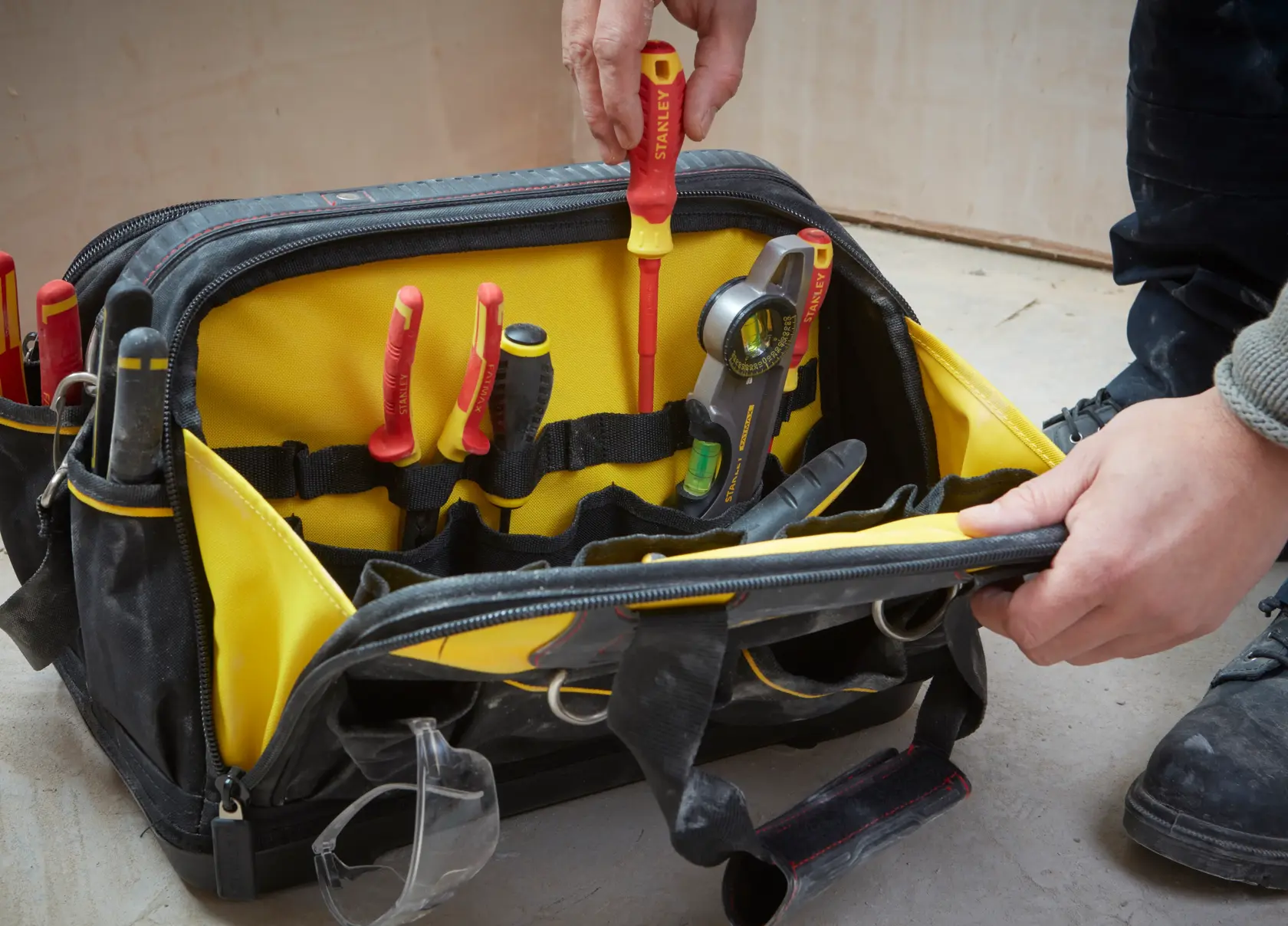 STANLEY FMST1-73607 tool bag with yellow interior, hand placing screwdriver, assorted tools visible.