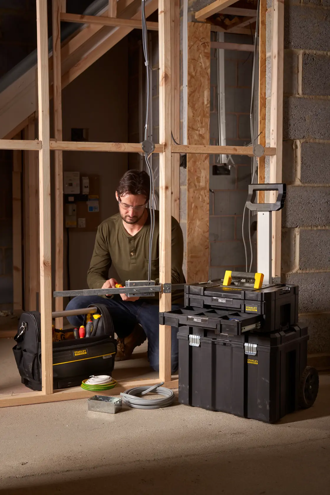 STANLEY FMST1-75753 black rolling tool box and organizer stack used at a construction site with a worker.