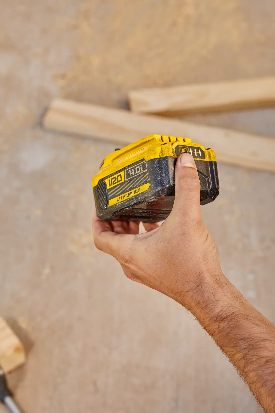 Photo of STANLEY SB204-KR V20 lithium-ion battery held in hand, construction wood background.