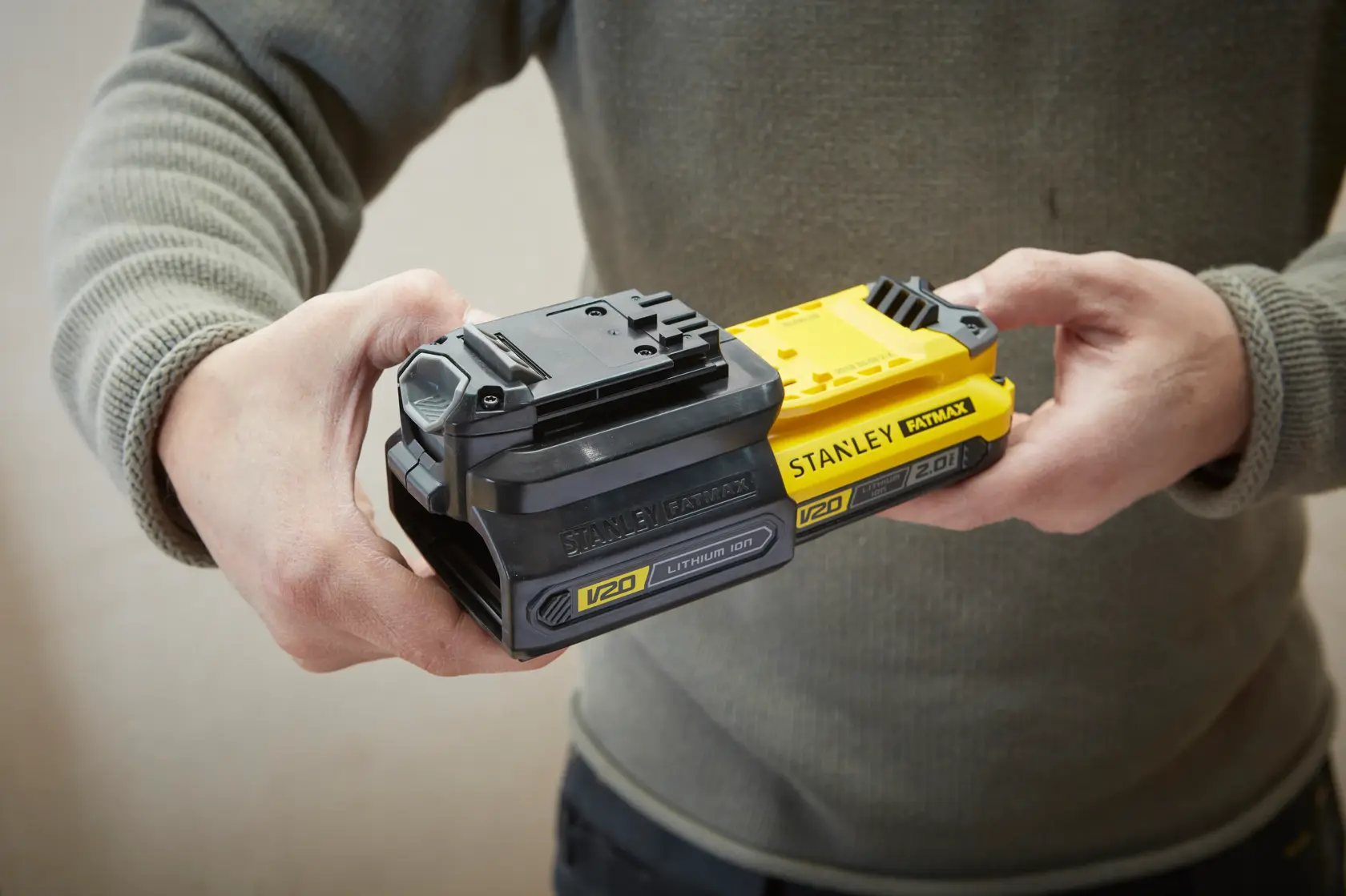 Photo of STANLEY SKU SBA100 V20 FATMAX lithium-ion batteries, person holding two units side by side.