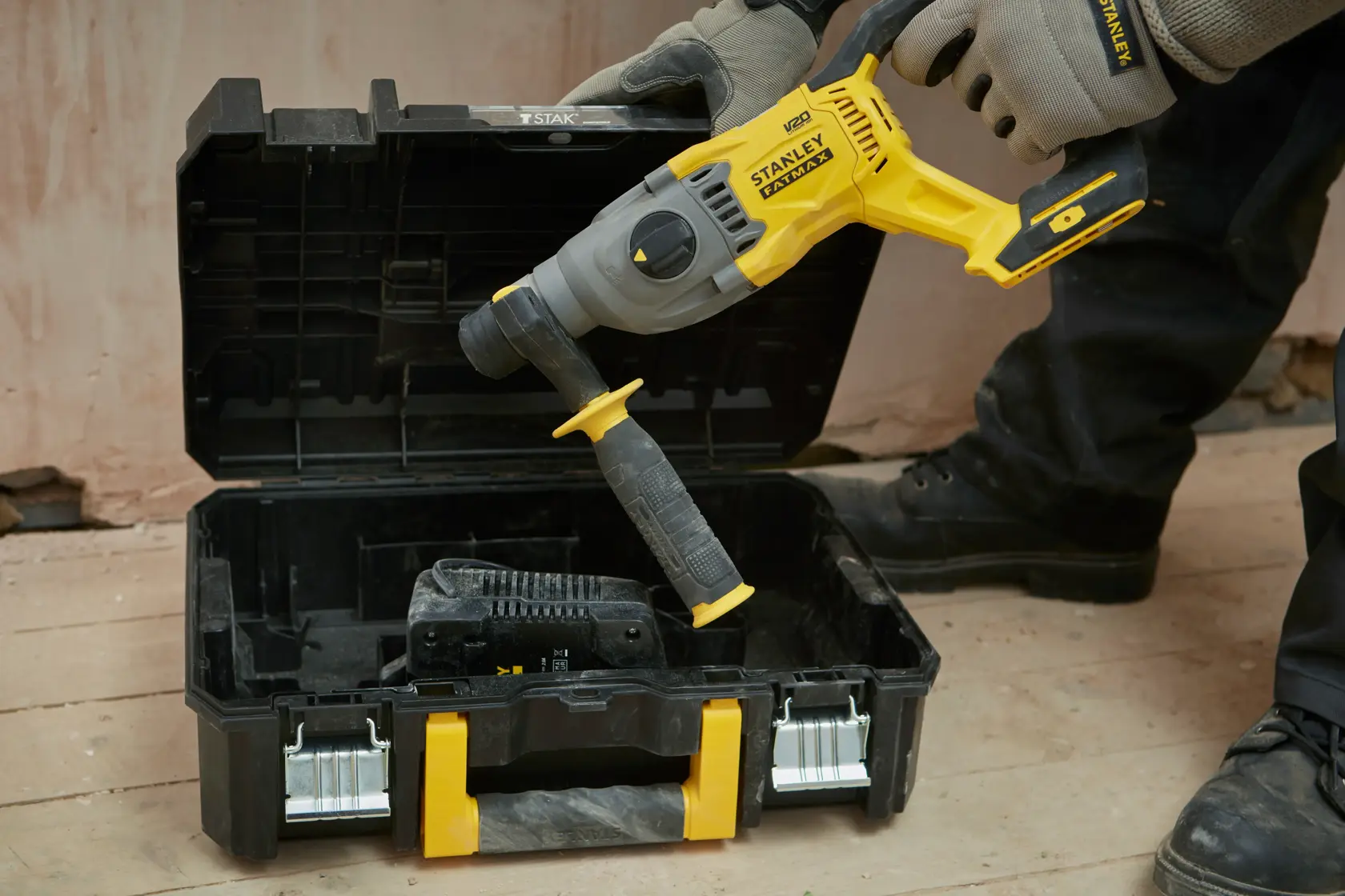 STANLEY SBH900M2K-B3 rotary hammer held above open black and yellow case on a construction site.