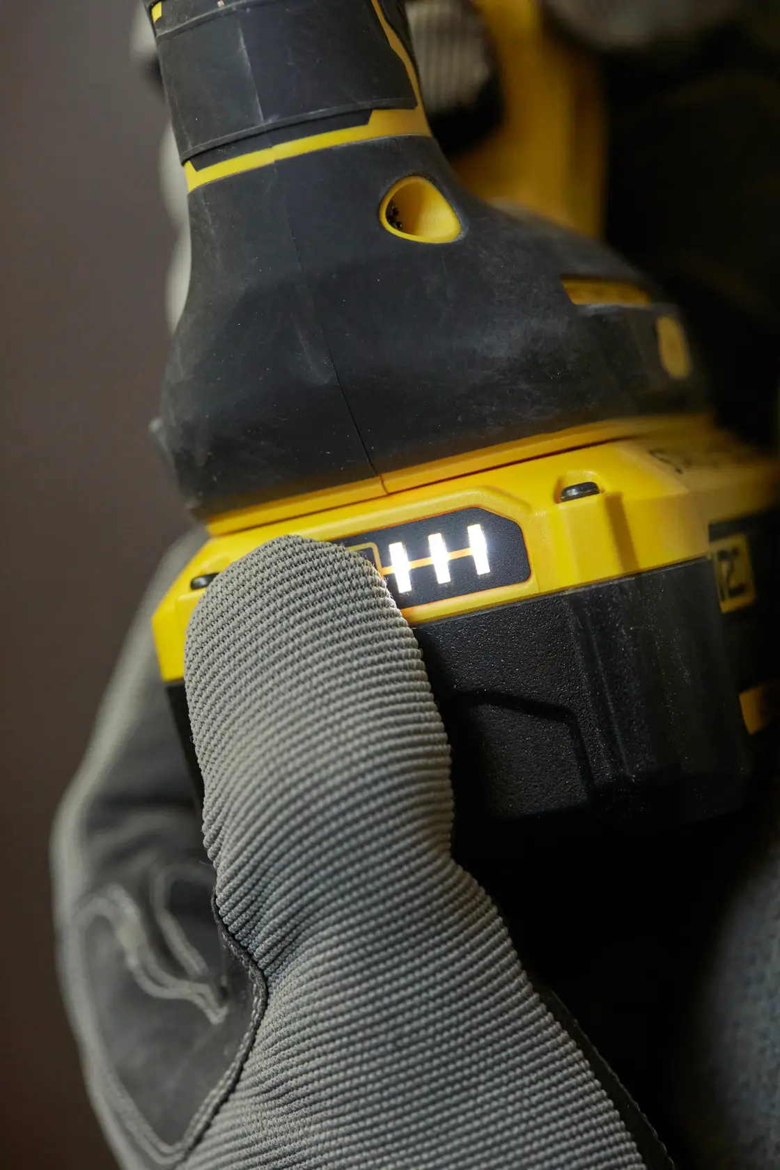 STANLEY SBH900M2K-B3 power tool battery pack close-up, glove pressing LED indicator, side angle.