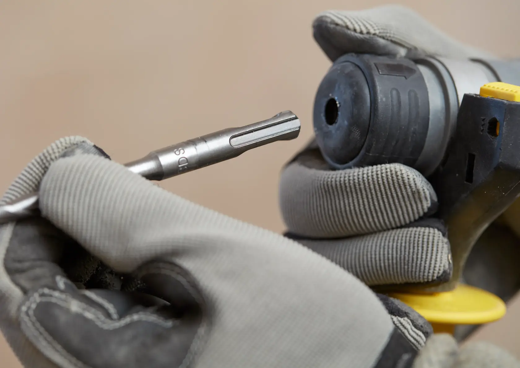 Stanley SBH900M2K-B3 drill bit being inserted into power tool, close-up photography of gloved hands.