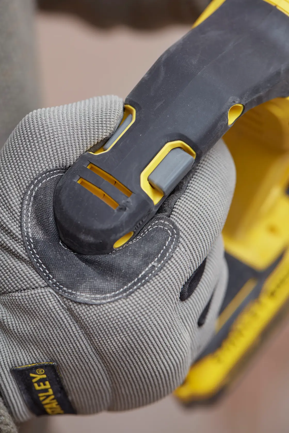 Stanley SBH900M2K-B3 power tool grip close-up, gray work glove holding black and yellow handle.