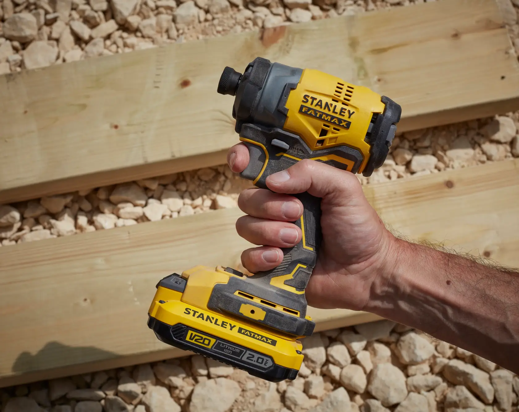 Photo of STANLEY SKU SBI810D2K-B3 cordless impact driver, yellow and black, handheld on construction site.