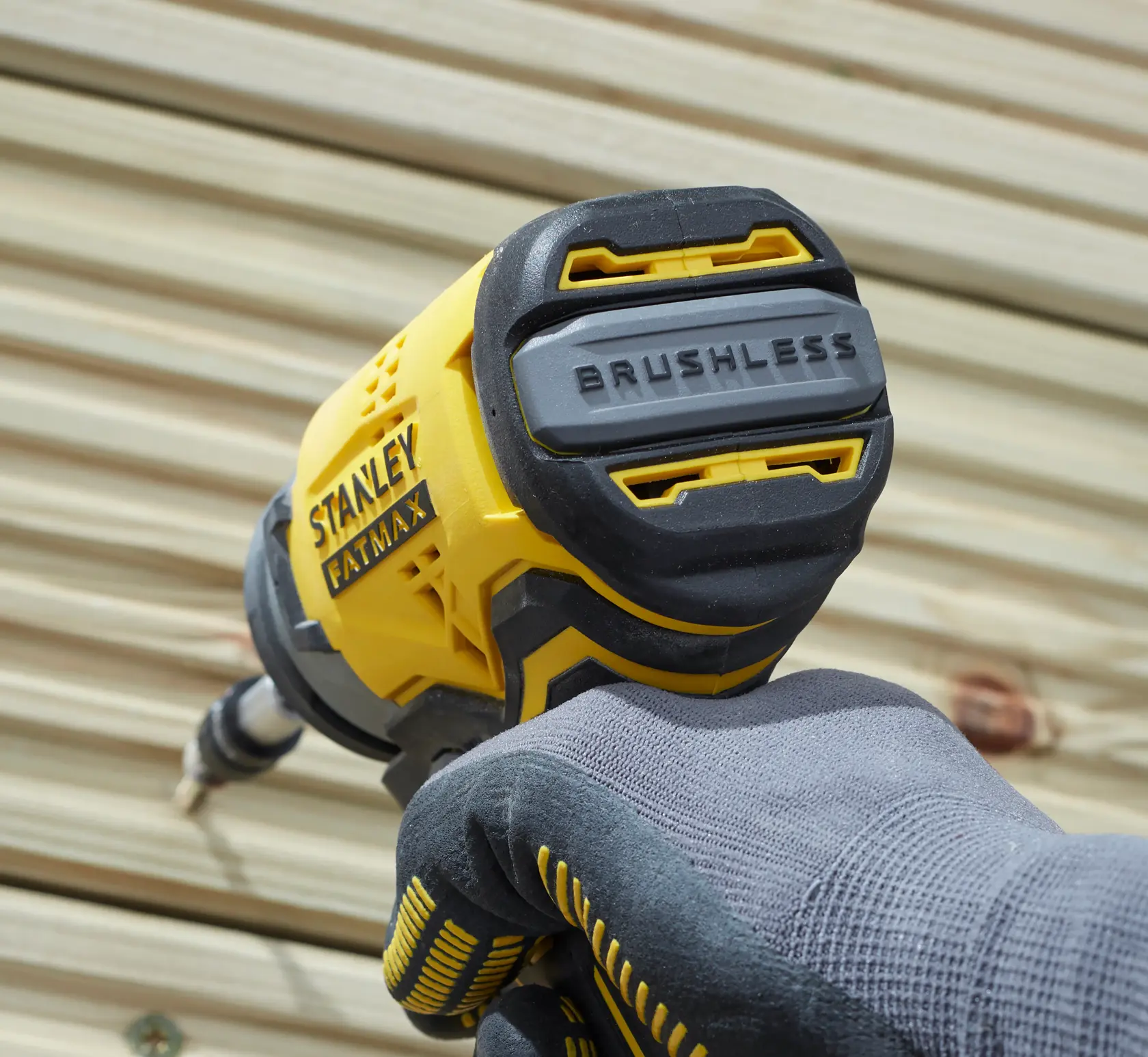 Stanley SBI810D2K-B3 impact driver, yellow and black, close-up in use, gloved hand, outdoors, FATMAX branding