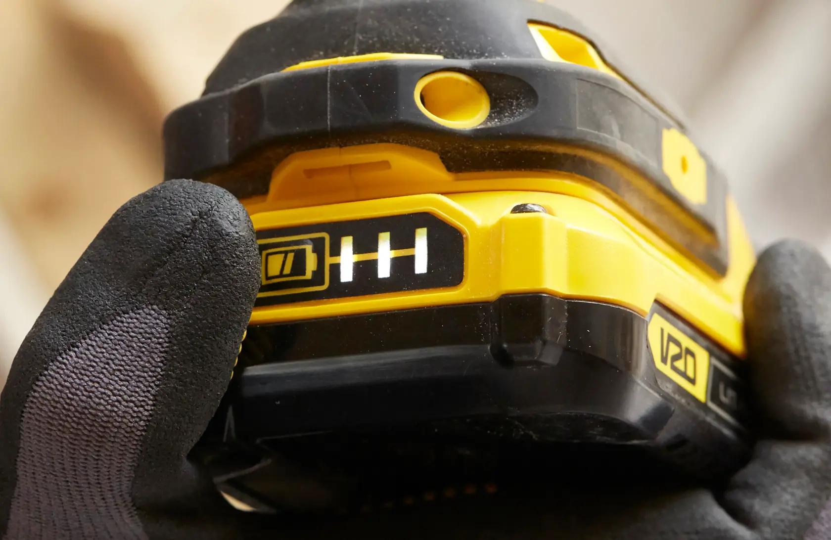 STANLEY SBI810D2K-B3 cordless tool battery close-up showing charge indicator, held by gloved hand.