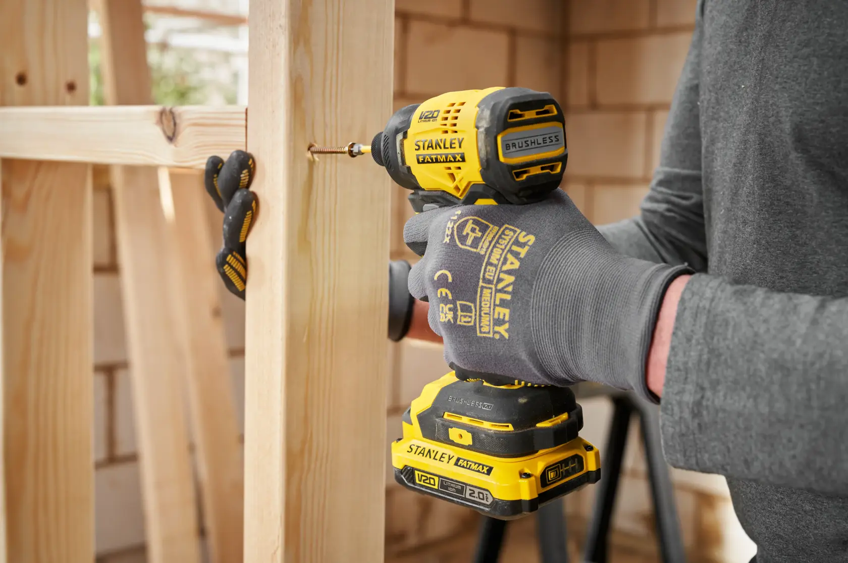STANLEY SBI811 cordless impact driver used to drill screw into wooden frame, close-up side angle