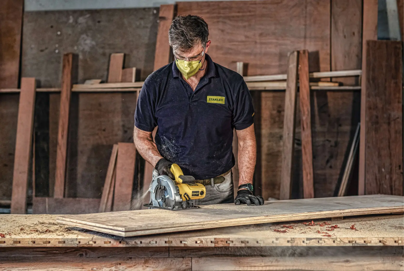 Stanley SC16 circular saw in use on wood in workshop, operator wearing Stanley shirt.