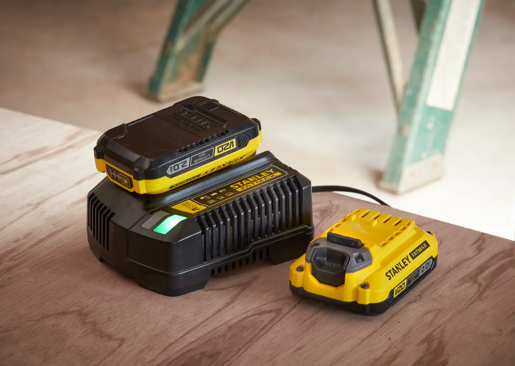 STANLEY SC200 battery charger and battery pack, yellow and black, angled view on wooden surface.
