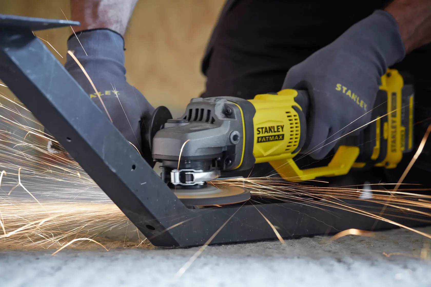 Stanley SCG400 angle grinder cutting metal with sparks, close-up photography of tool in use.