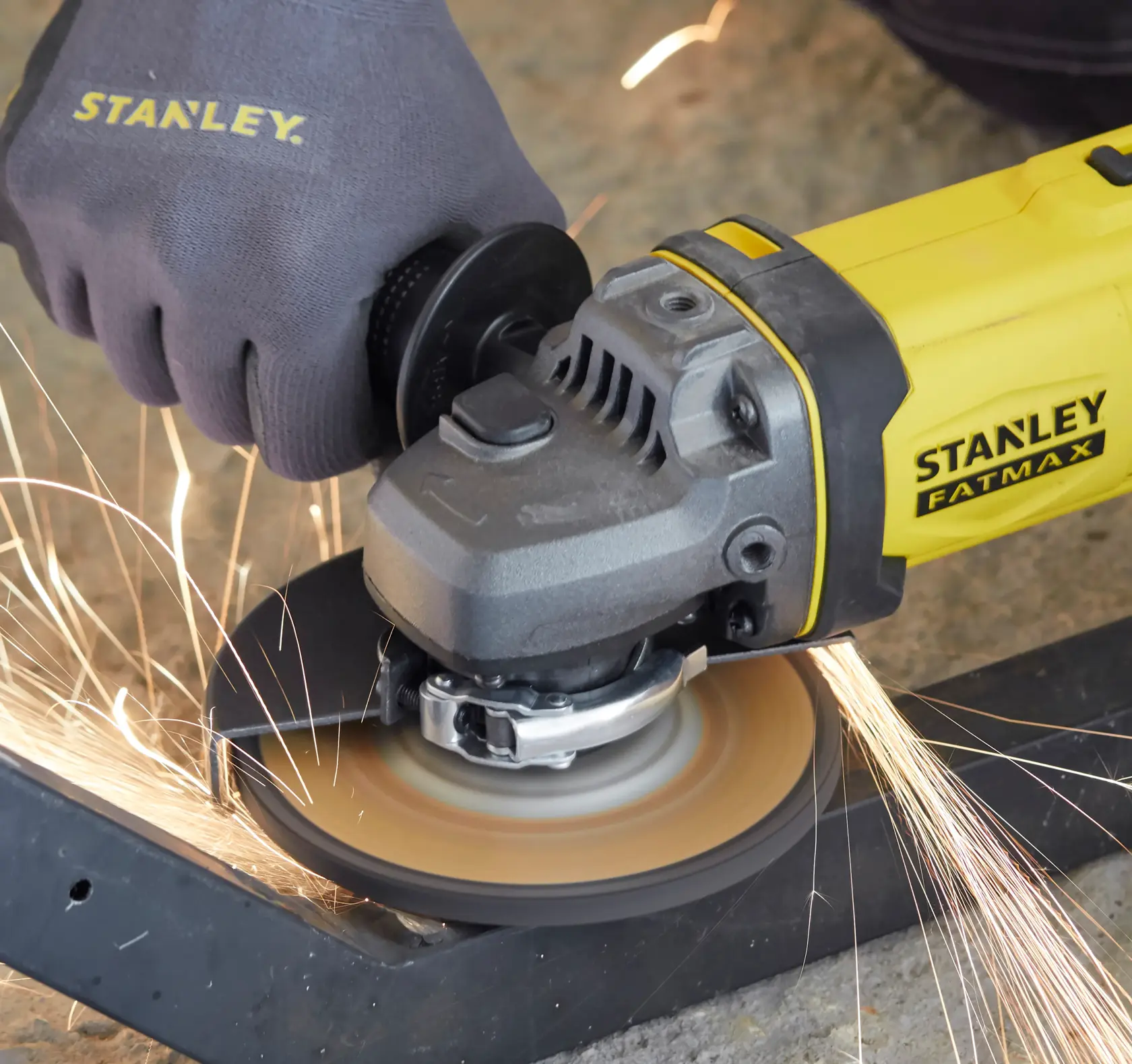 STANLEY SCG400 angle grinder cutting metal with safety glove, side angle photo.