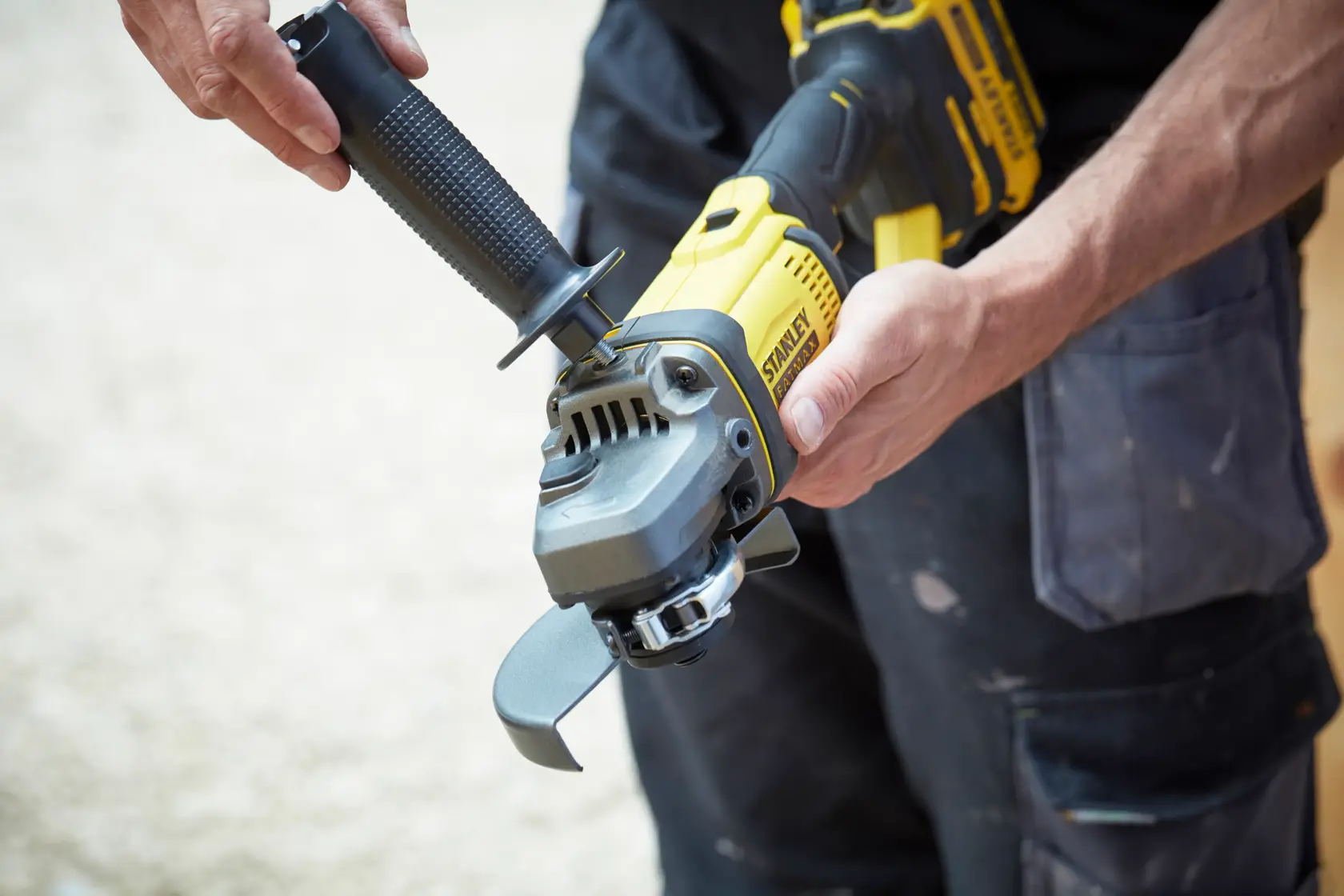 STANLEY SCG400 angle grinder held by a person, yellow and black design, close-up view.