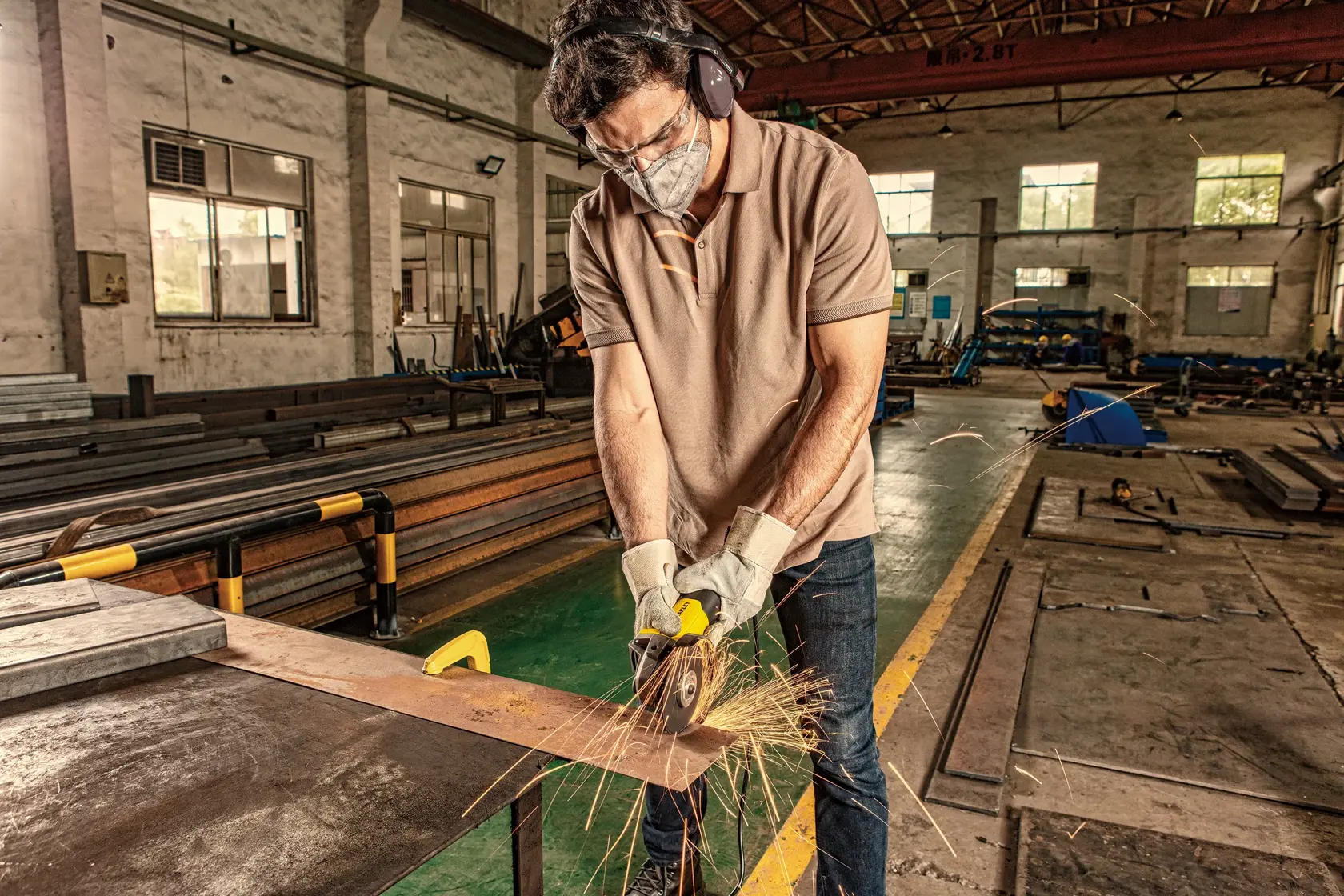 STANLEY SG7100 angle grinder in use at industrial workshop, sparks flying from metal cutting.