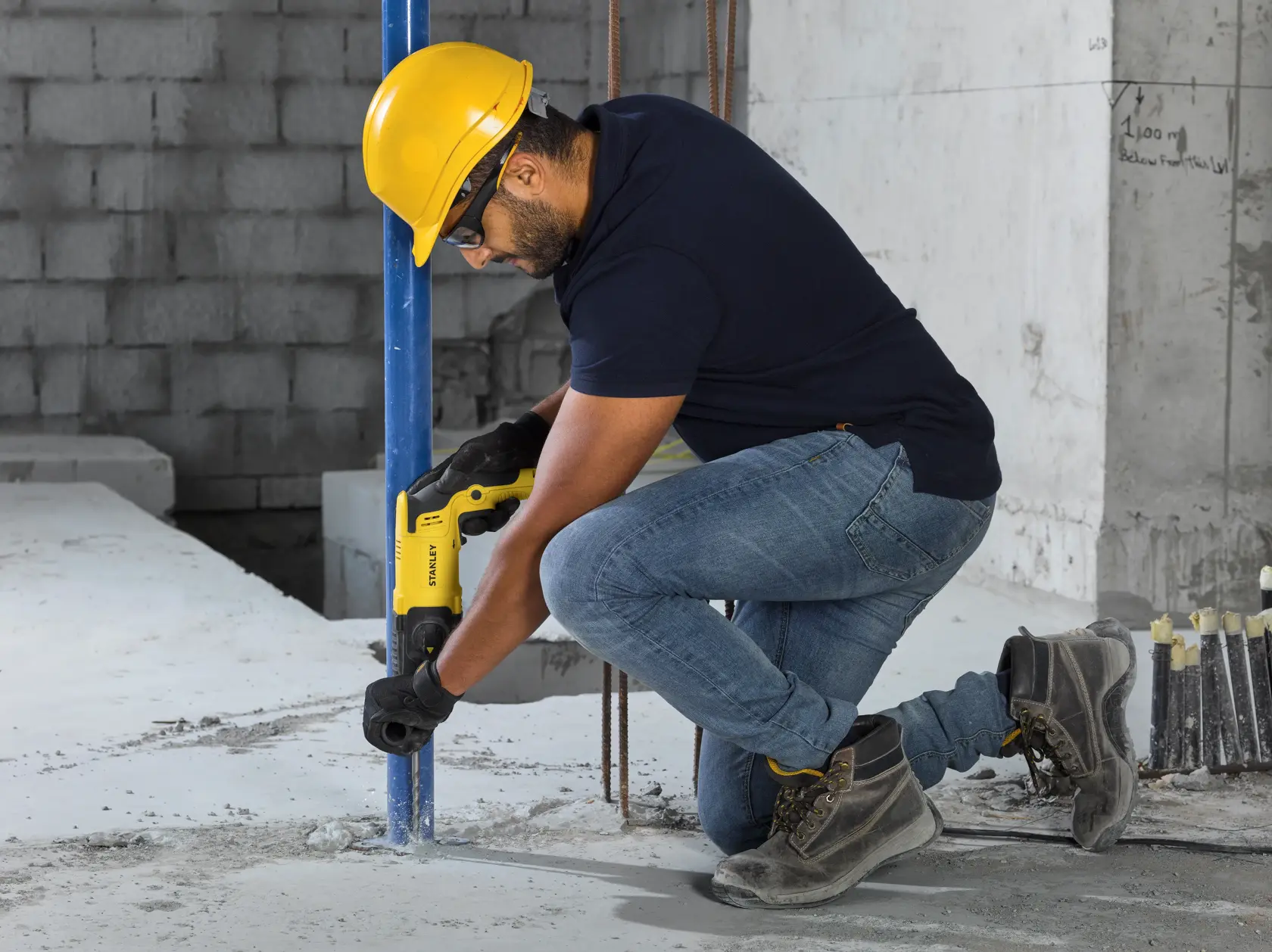 STANLEY SHR263K-BR rotary hammer drill in use on wood, worker wearing yellow hard hat and black uniform.