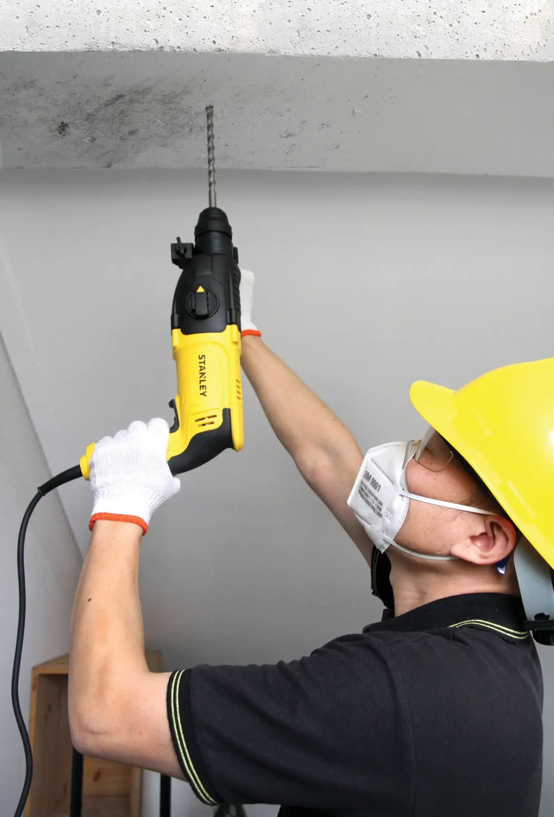 Stanley SHR263K-BR rotary hammer drill in use, yellow and black, drilling concrete ceiling.