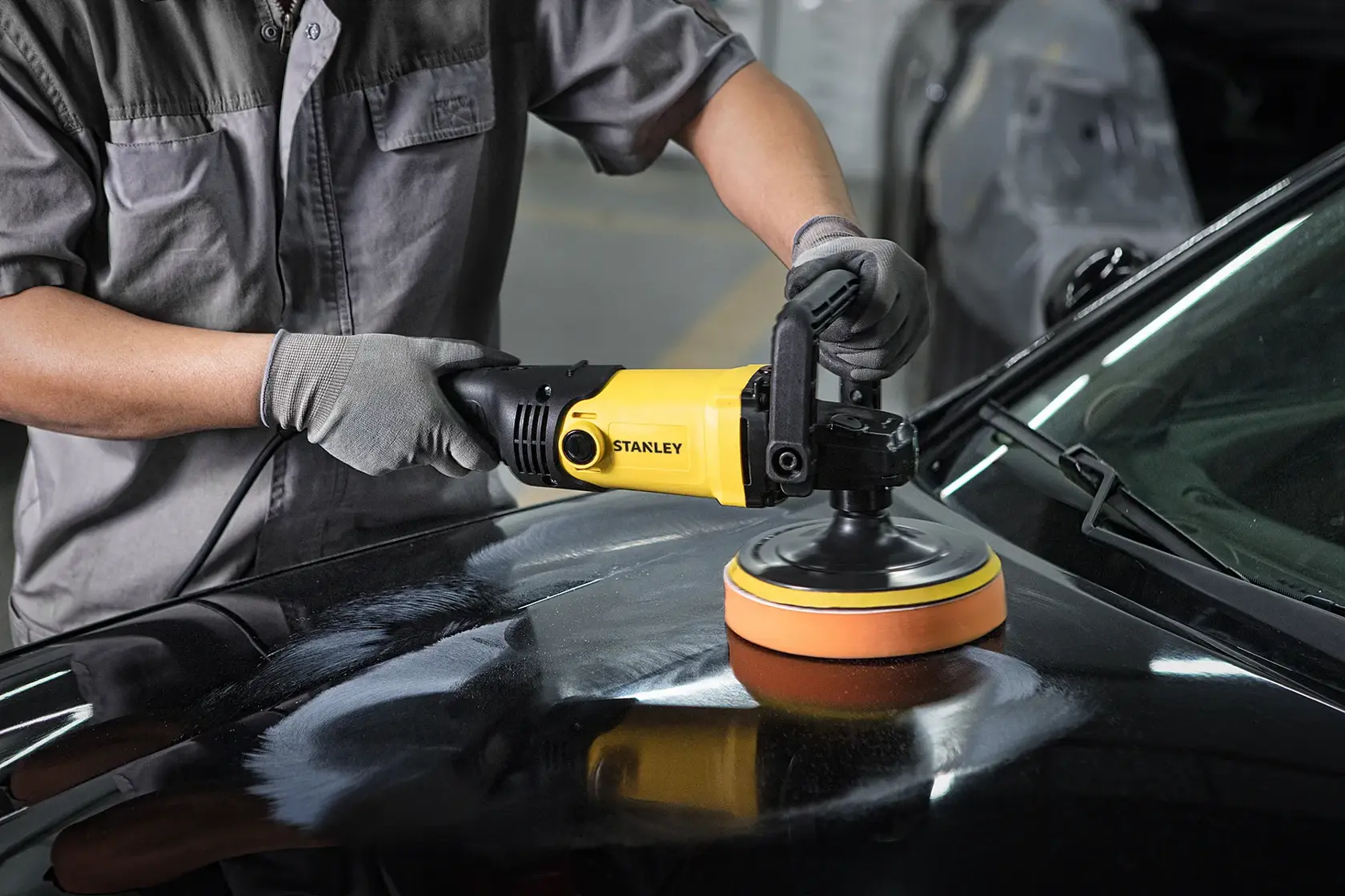 Stanley SP137 photography of yellow polisher in use on black car hood, close-up angle.