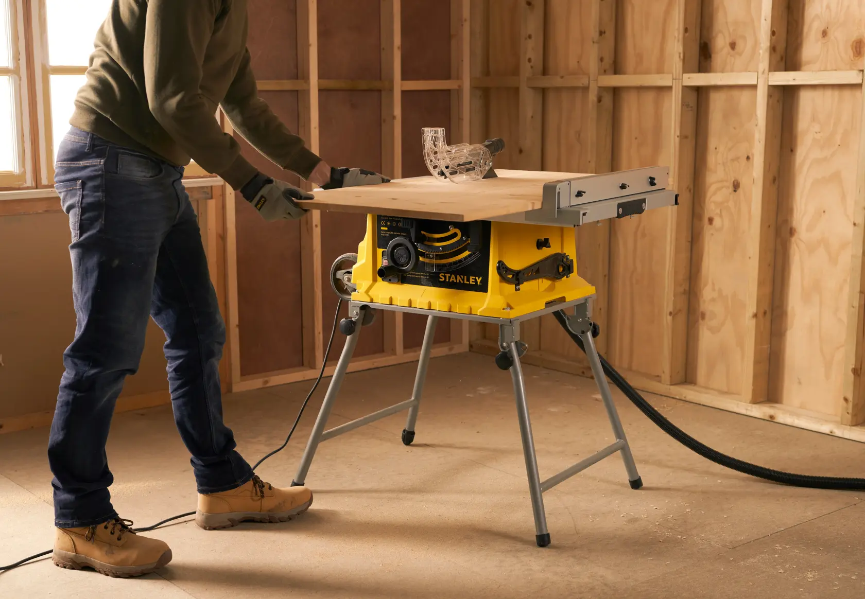 STANLEY SST1800 table saw in use on a jobsite, yellow base, extended work surface, wood cutting in progress.